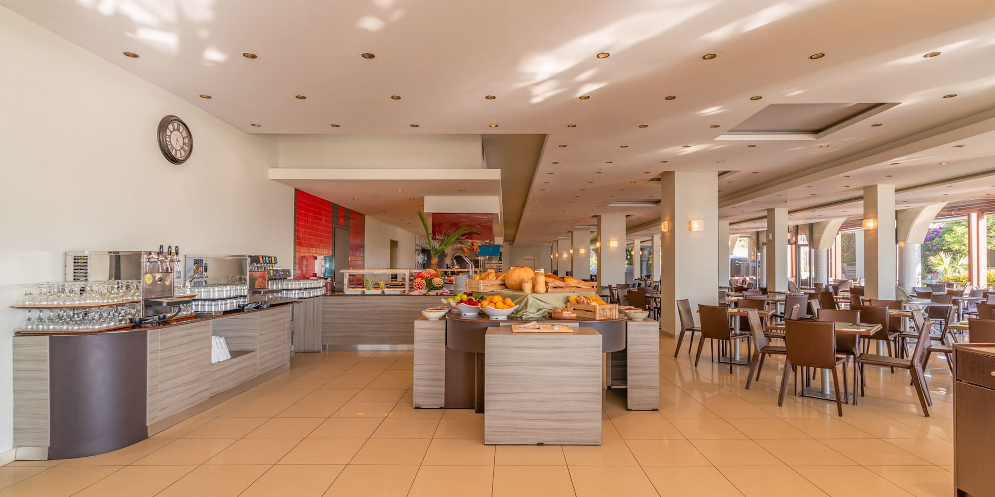 Modern hotel buffet area with breakfast food and seating.