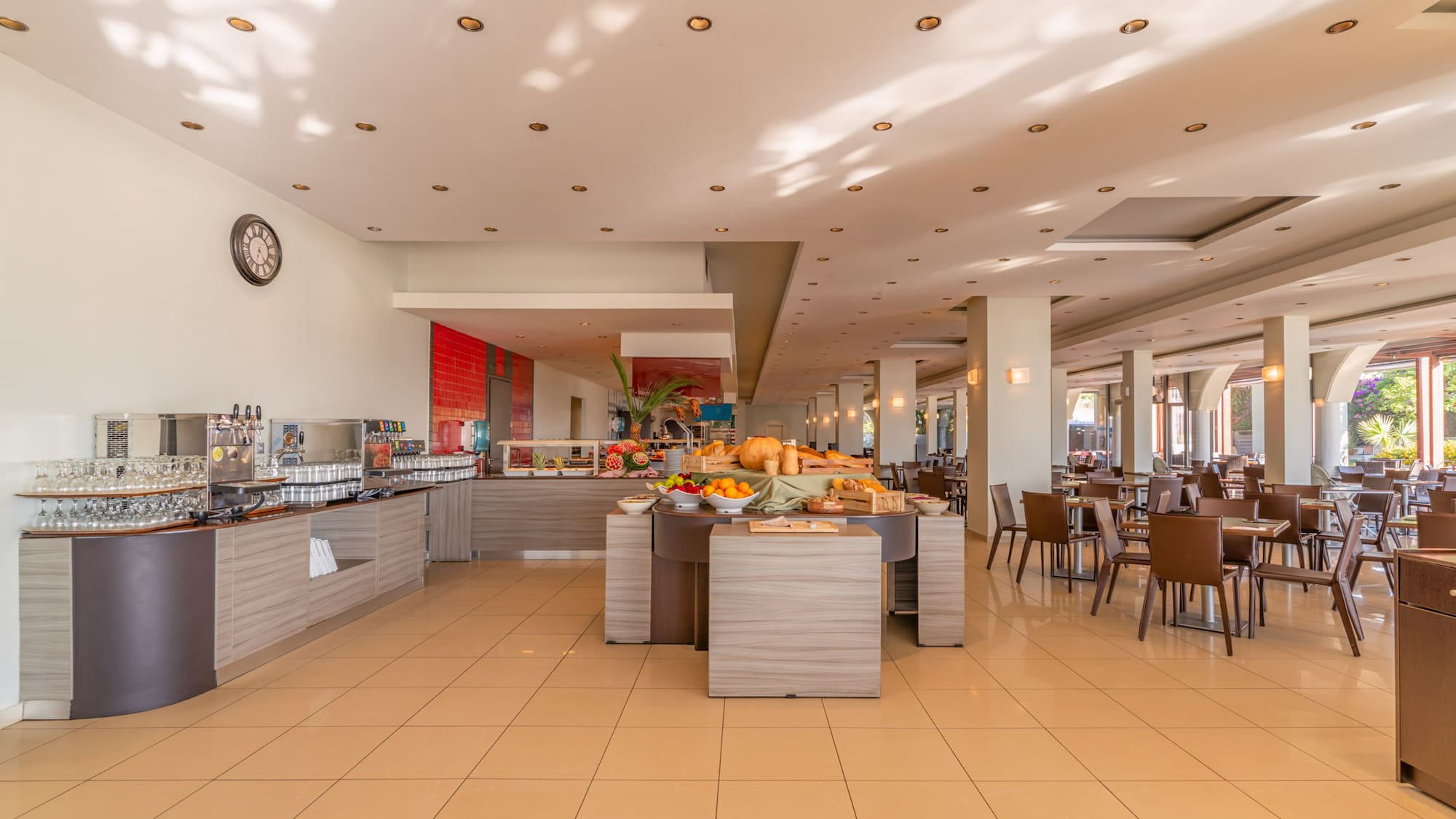 Modern hotel buffet area with breakfast food and seating.