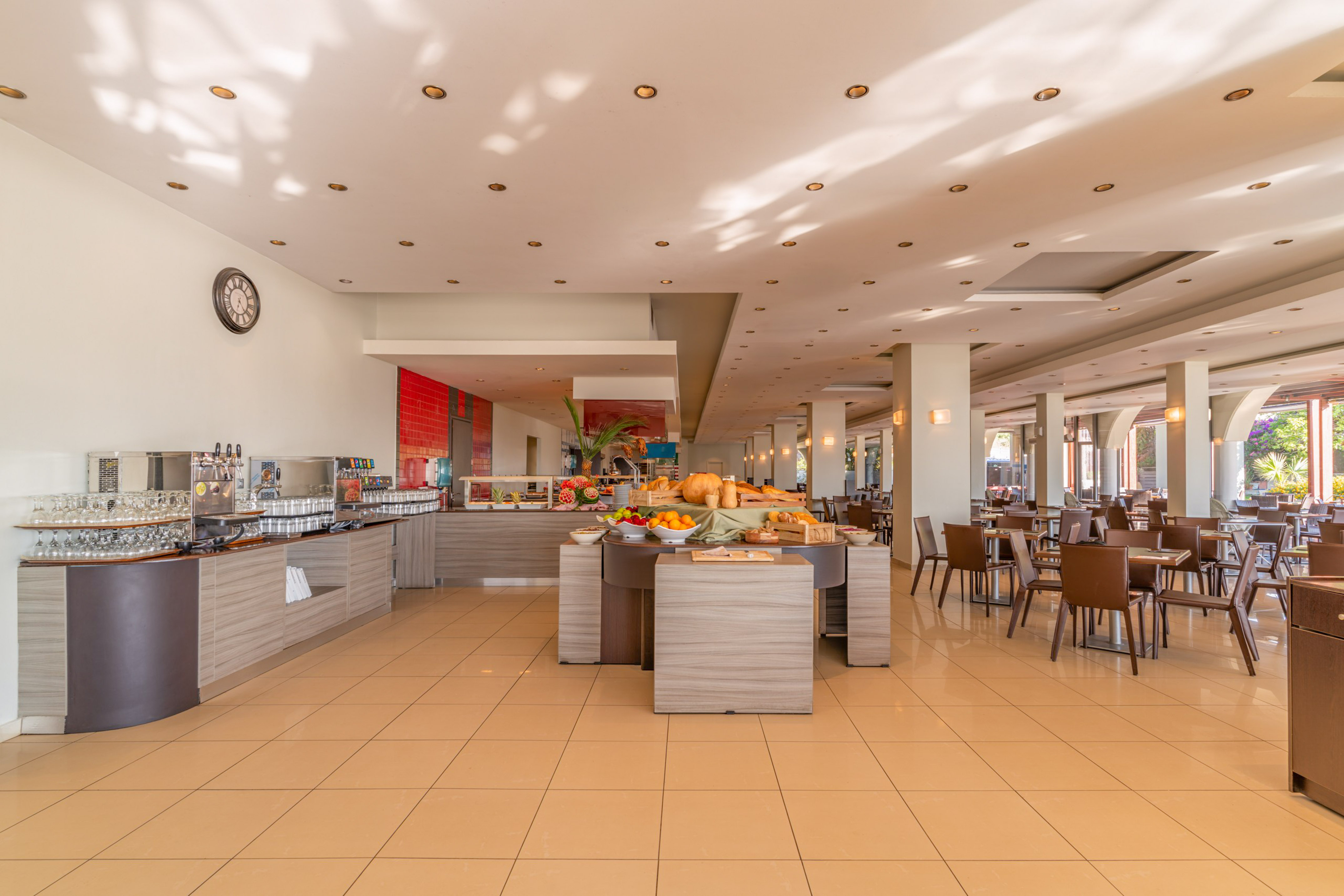 Modern hotel buffet area with breakfast food and seating.