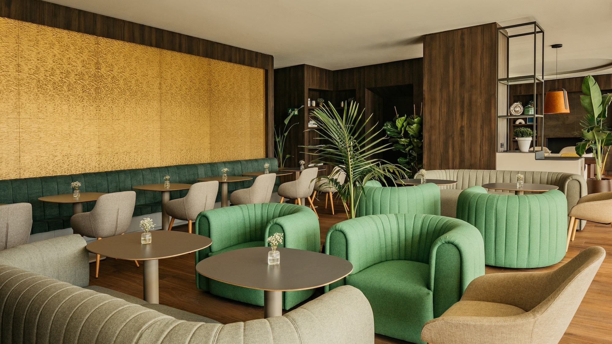 Modern cafe lounge with green seating, wood tables, yellow wall, and plants.