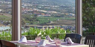 a table and chairs outside with a view of a valley and mountains