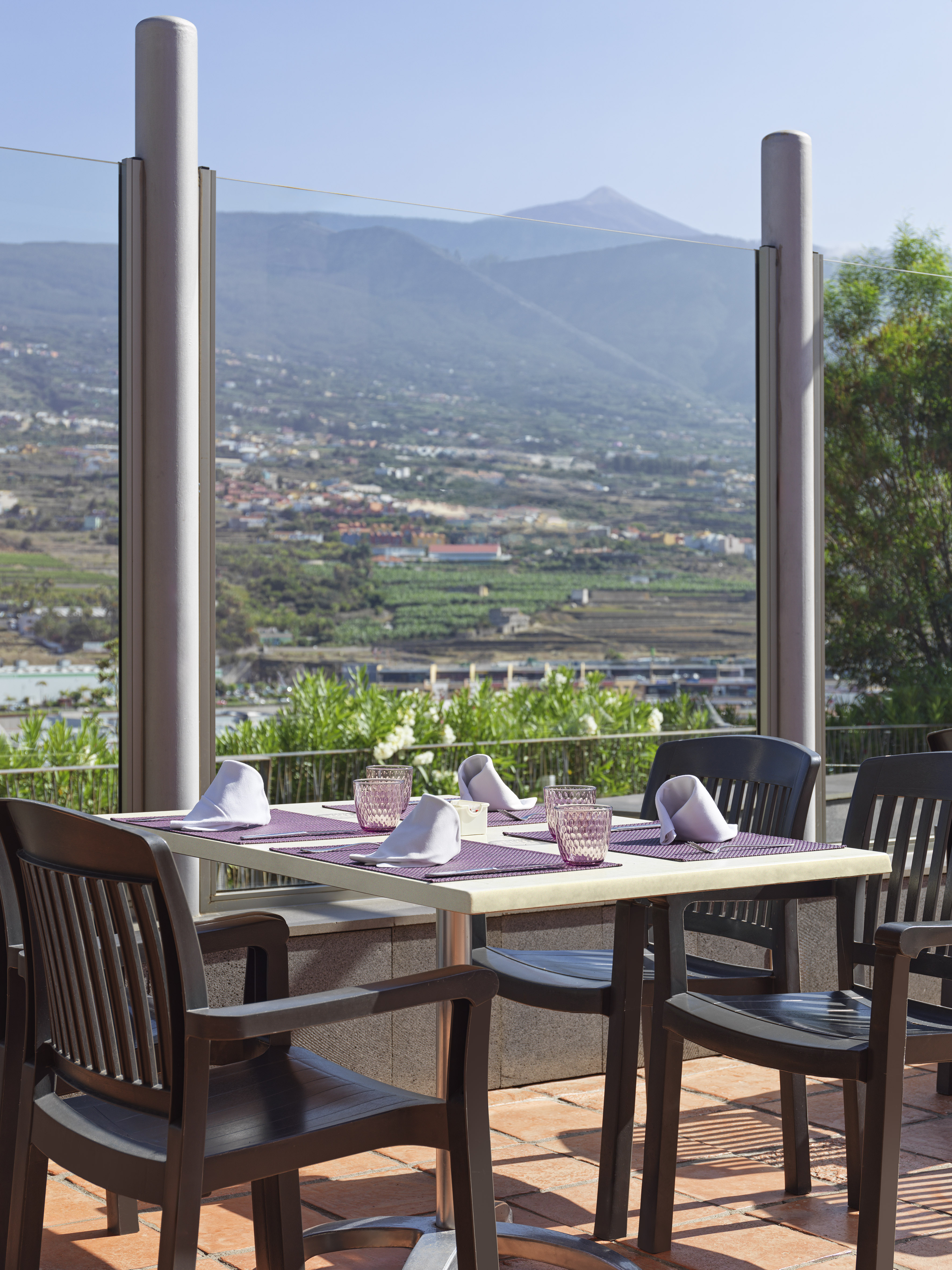 Outdoor restaurant terrace, table set for four with scenic Teide mountain view.