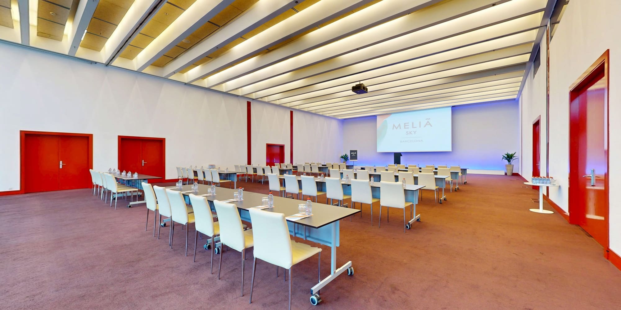 Modern Melia Sky Barcelona conference room with classroom seating and projector.