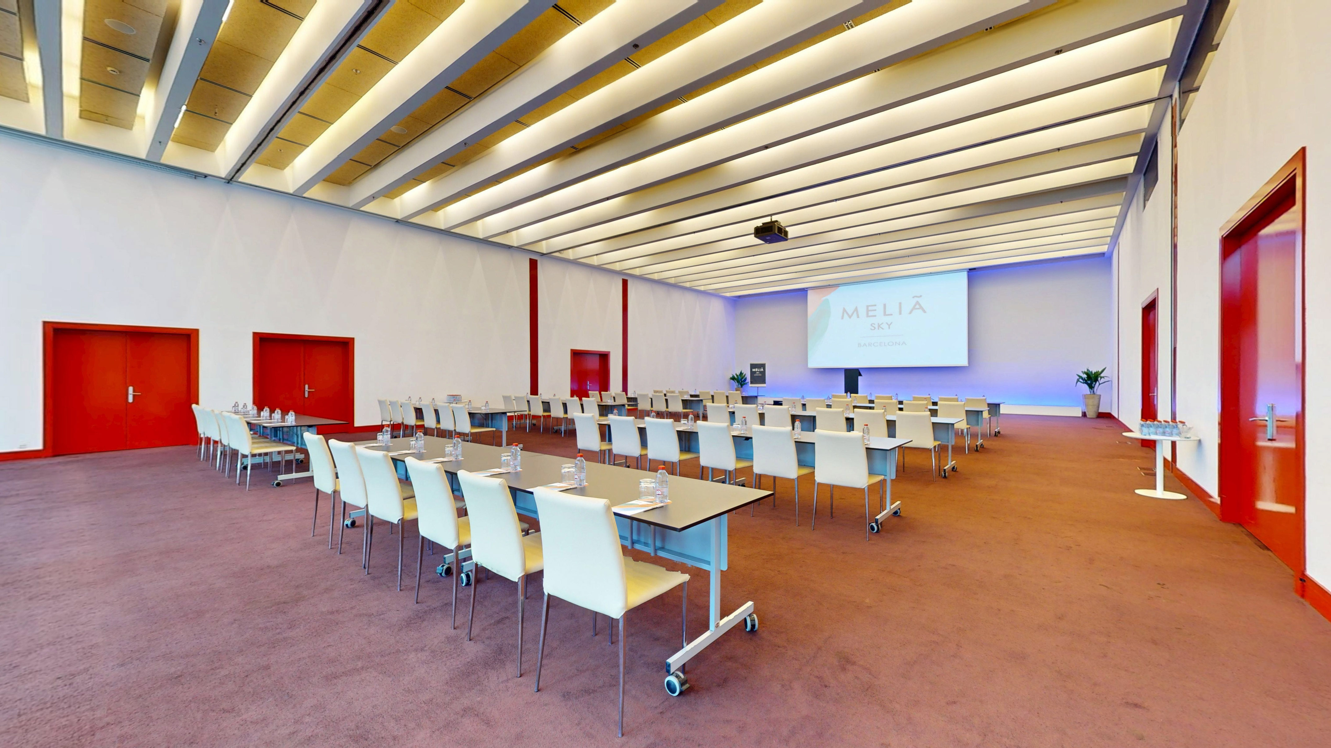 Modern Melia Sky Barcelona conference room with classroom seating and projector.