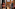 Dry ager displaying beef cuts, meat chart on wood wall, blurred chef walking.