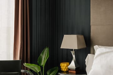 a bed with a lamp and a plant in a room