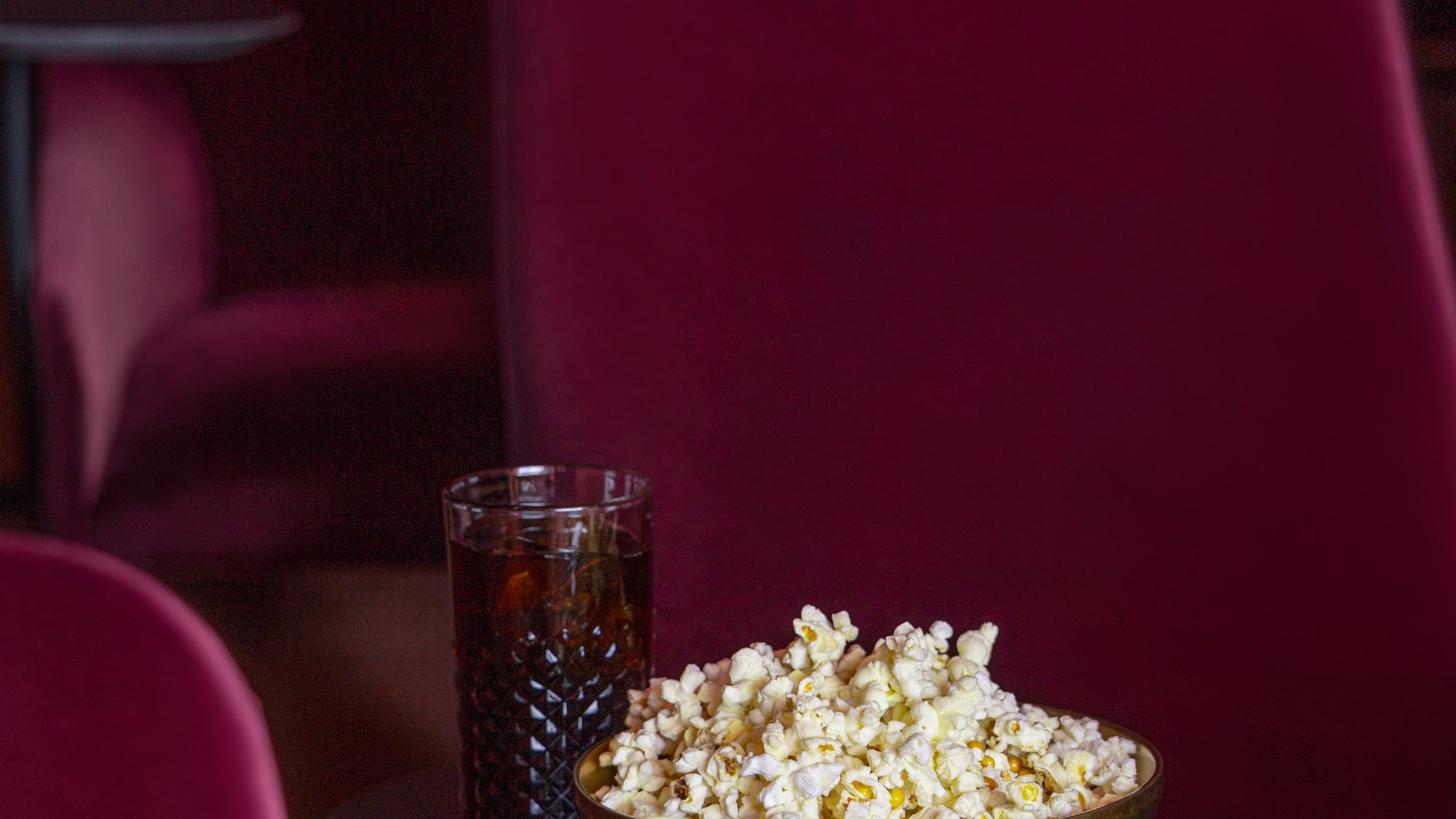 a bowl of popcorn and a glass of soda on a table