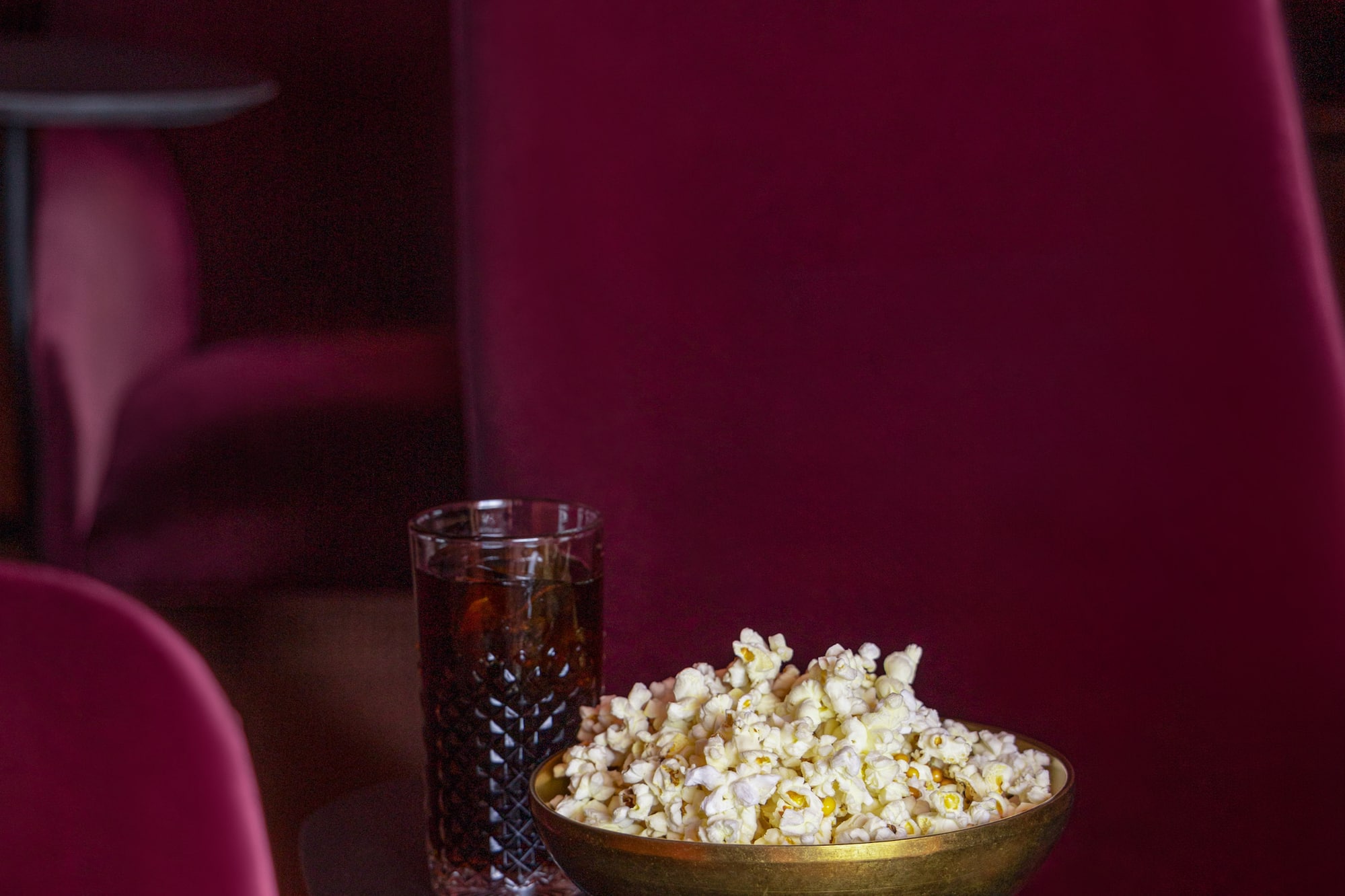 a bowl of popcorn and a glass of soda on a table