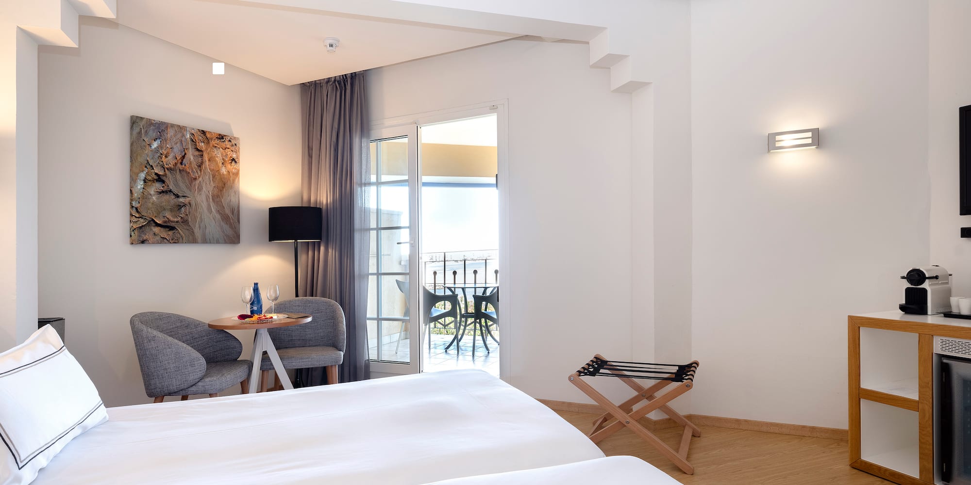 a room with white beds and a table and chairs