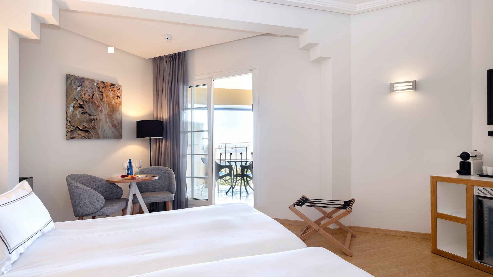 a room with white beds and a table and chairs