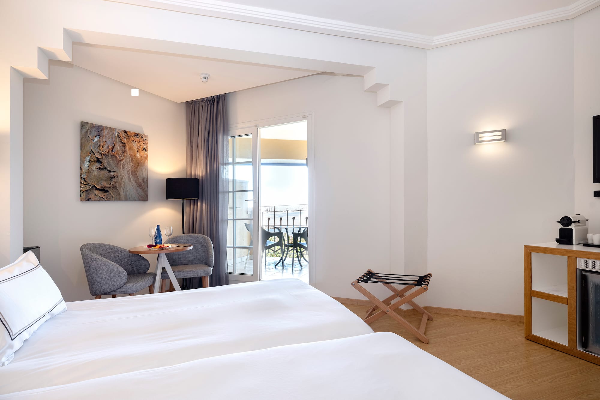 a room with white beds and a table and chairs