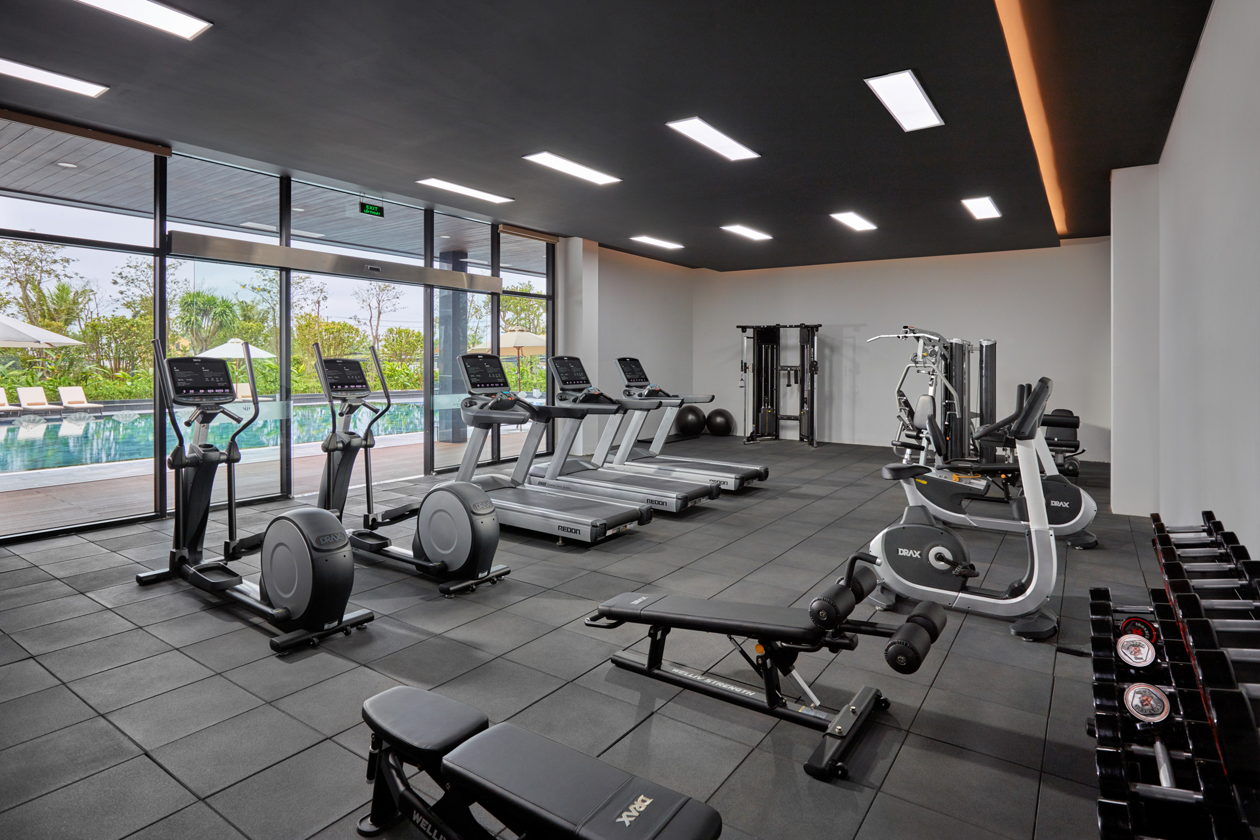 Sleek fitness center with diverse gym equipment and panoramic pool views.