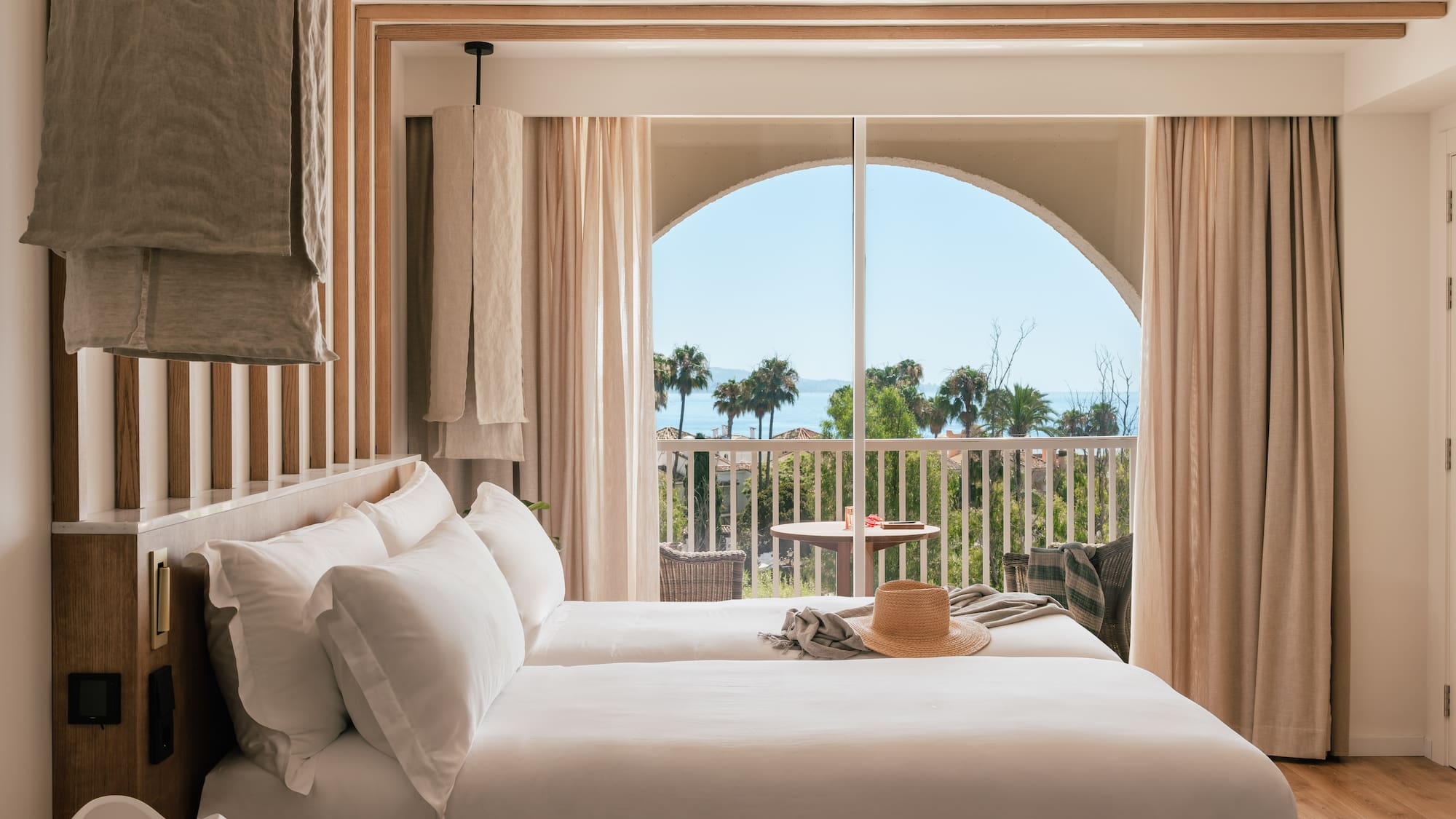 a room with a bed and a balcony overlooking the ocean