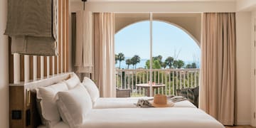 a room with a bed and a balcony overlooking the ocean
