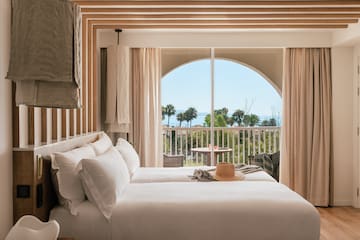 a room with a bed and a balcony overlooking the ocean