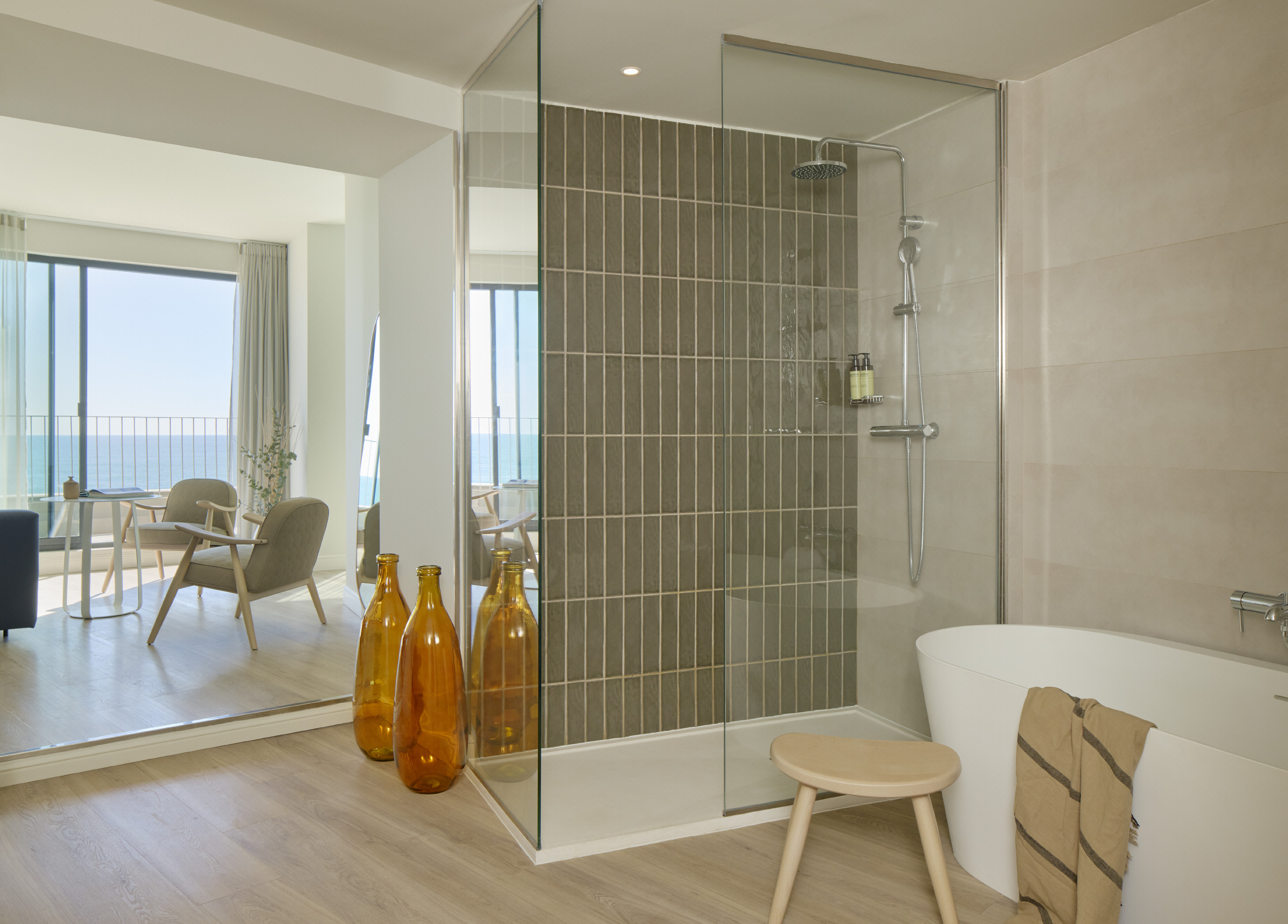 Modern bathroom suite with glass shower, freestanding tub, and ocean view.
