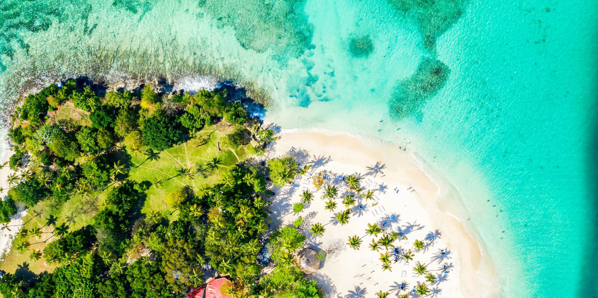 Isla caribeña vista aérea: playa arena blanca, palmeras, mar turquesa, lancha.