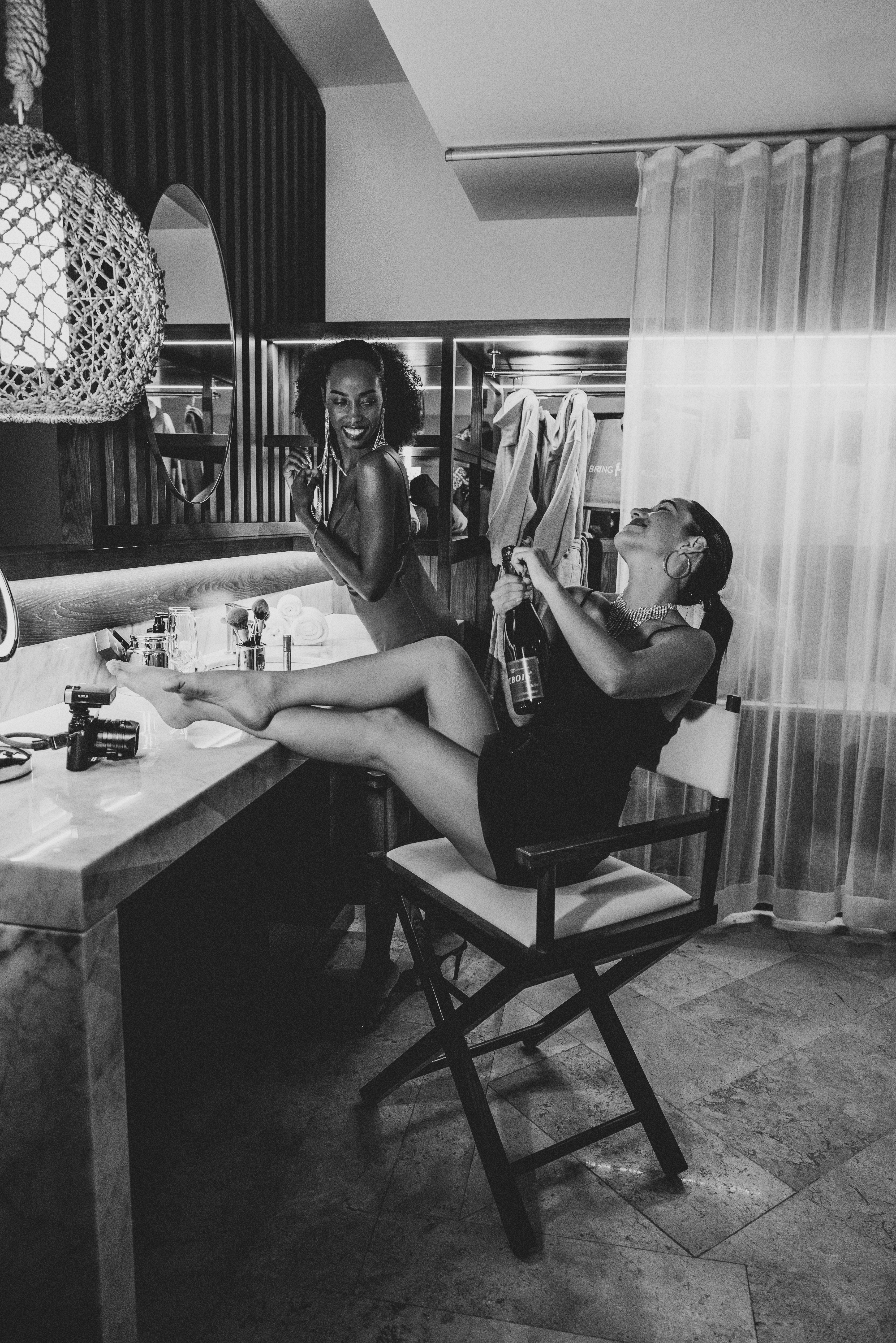 Black and white: Two women celebrating with champagne at a vanity.