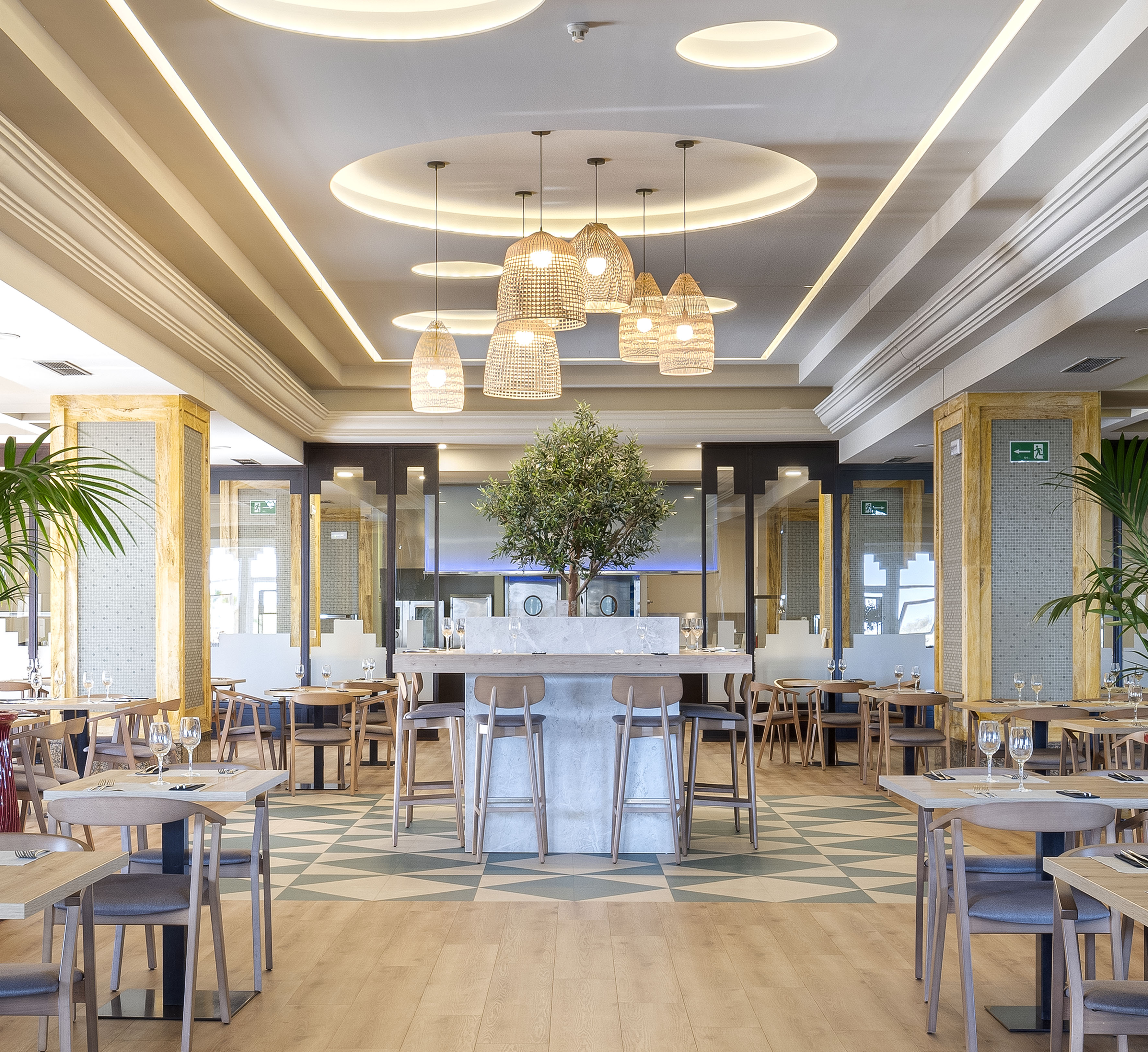 Bright modern restaurant with wooden tables, woven pendant lights, and central bar.