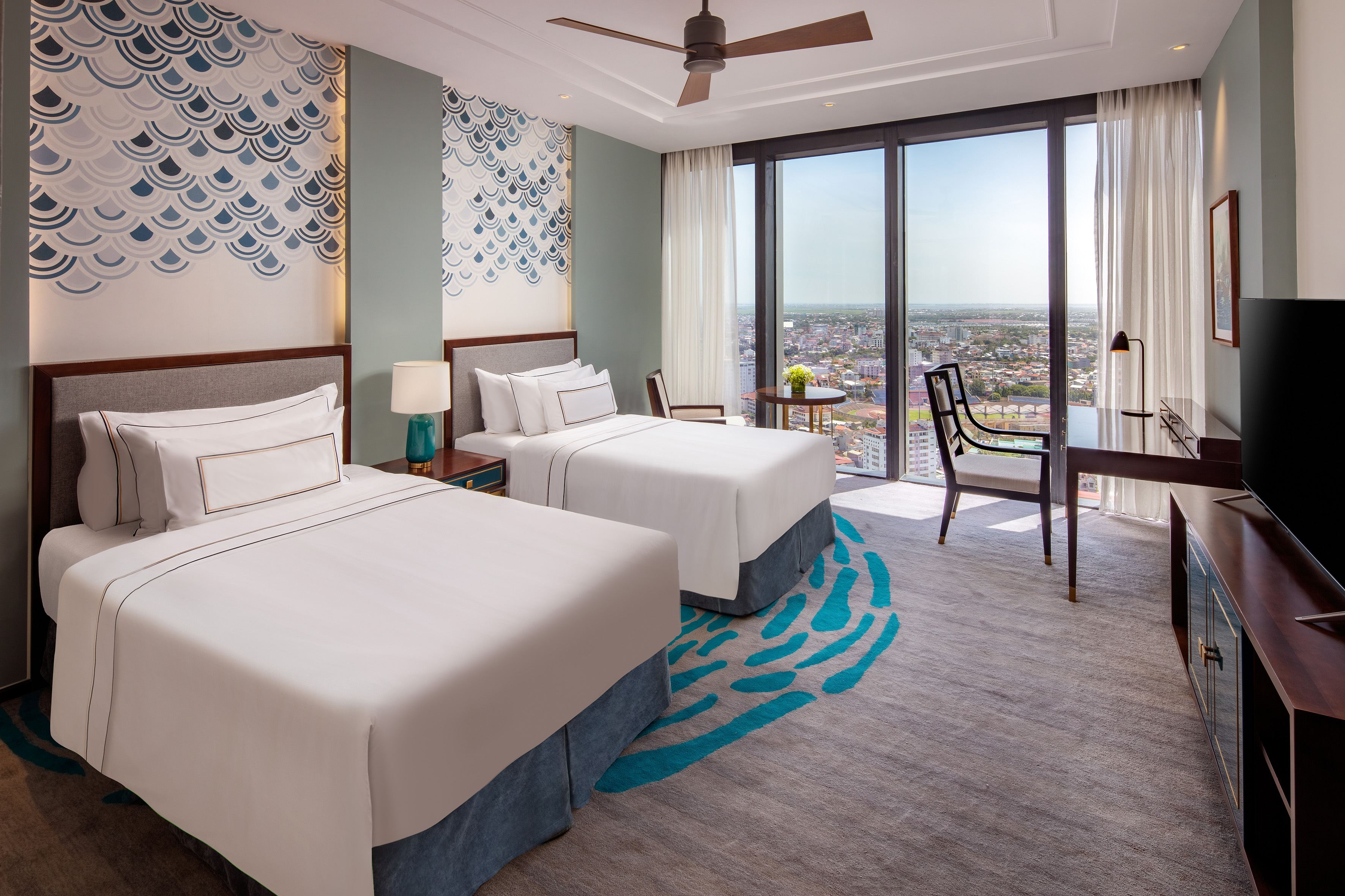 Luxury hotel room with twin beds, panoramic city view, and stylish interior.