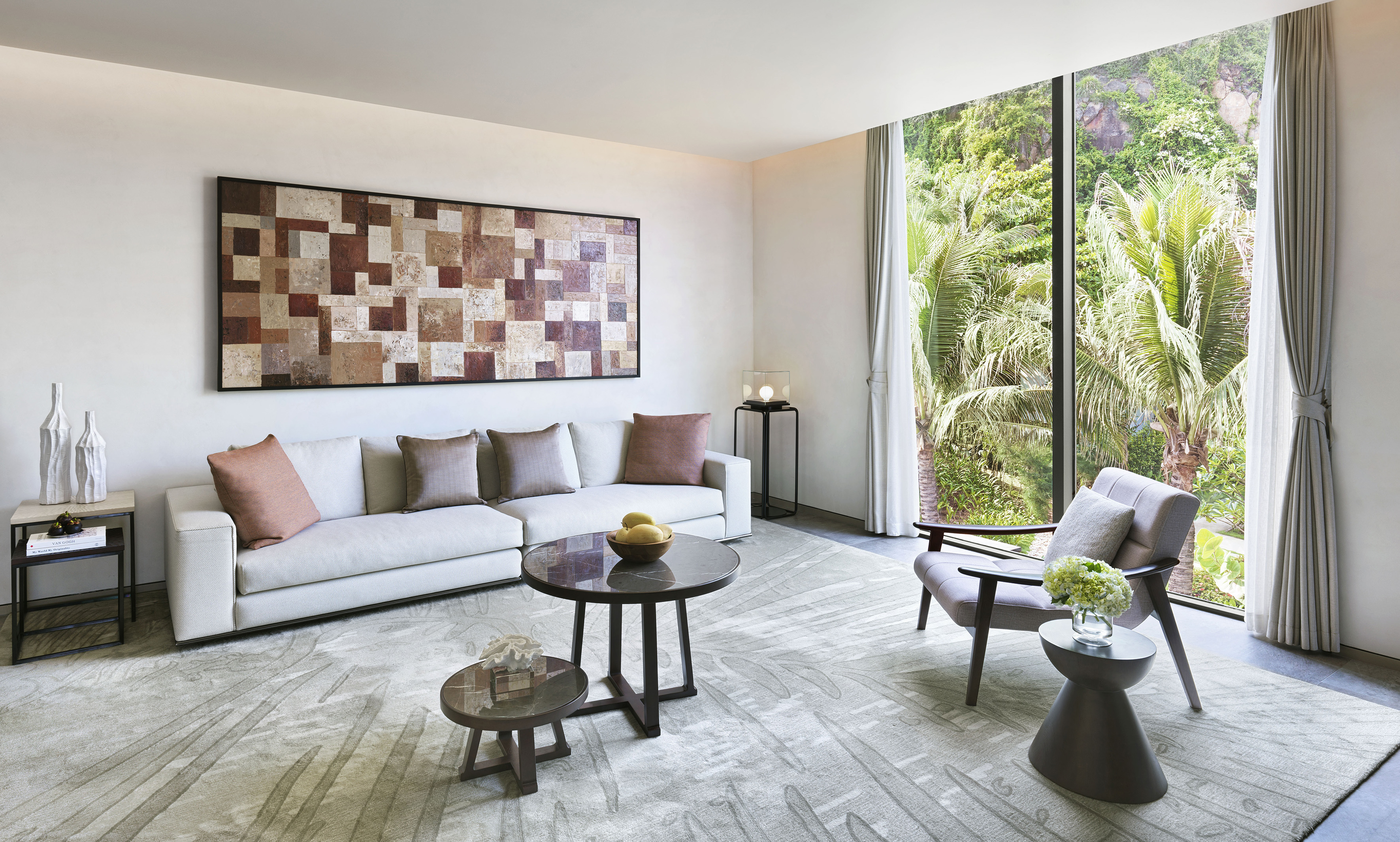 Modern living room with white sofa, abstract art, and tropical window view.