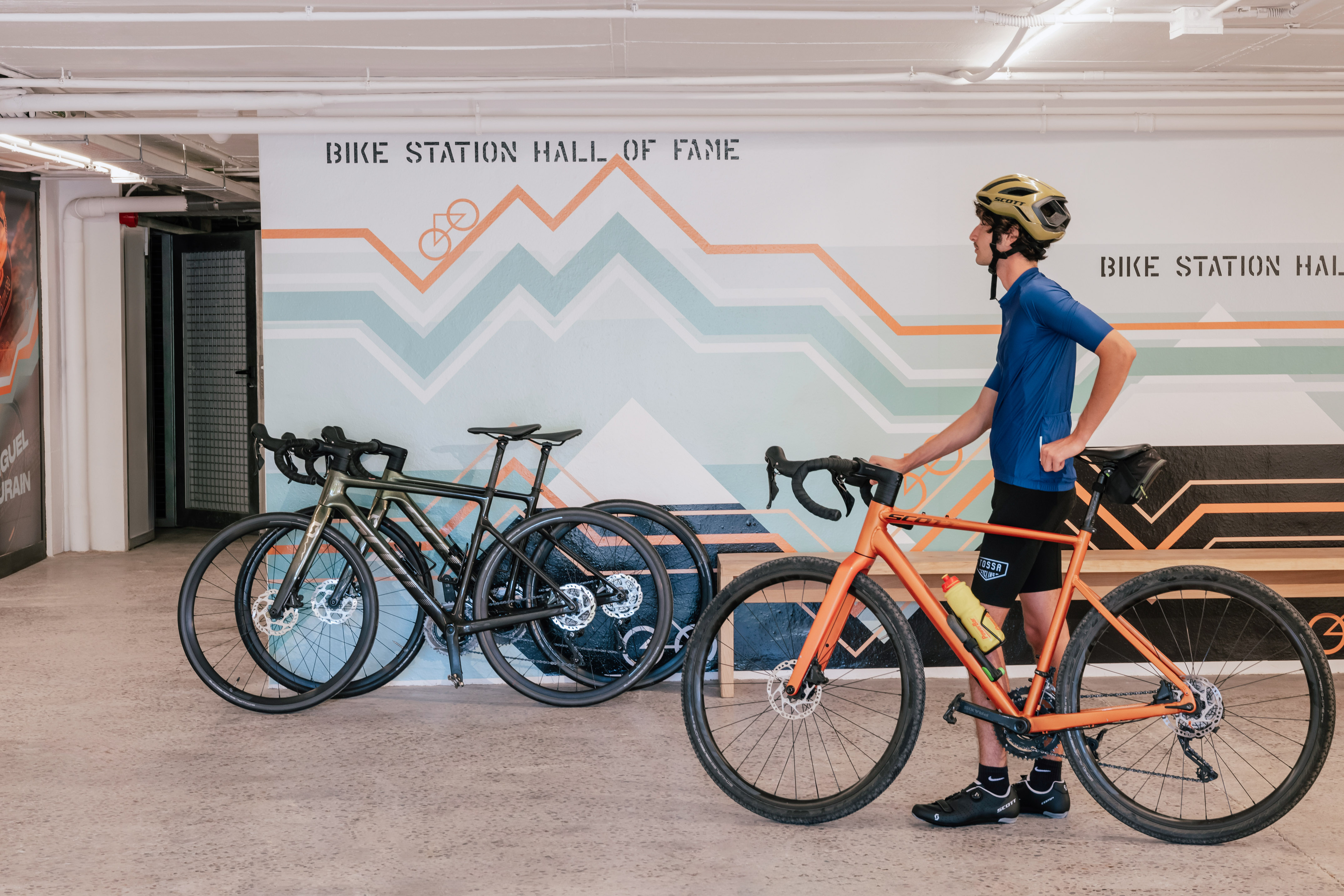 Cyclist with orange gravel bike at 'Bike Station Hall of Fame'.
