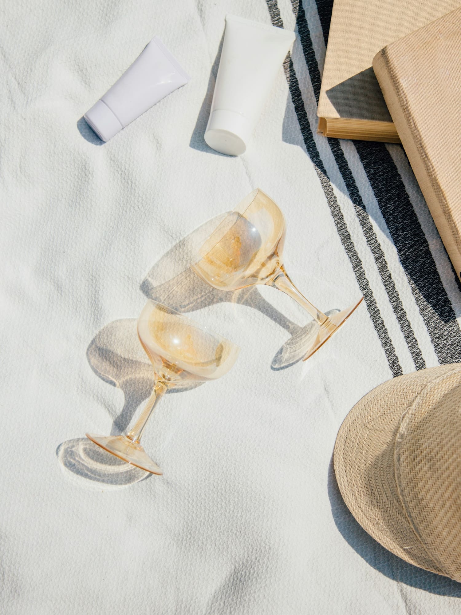 a pair of wine glasses and a hat on a blanket