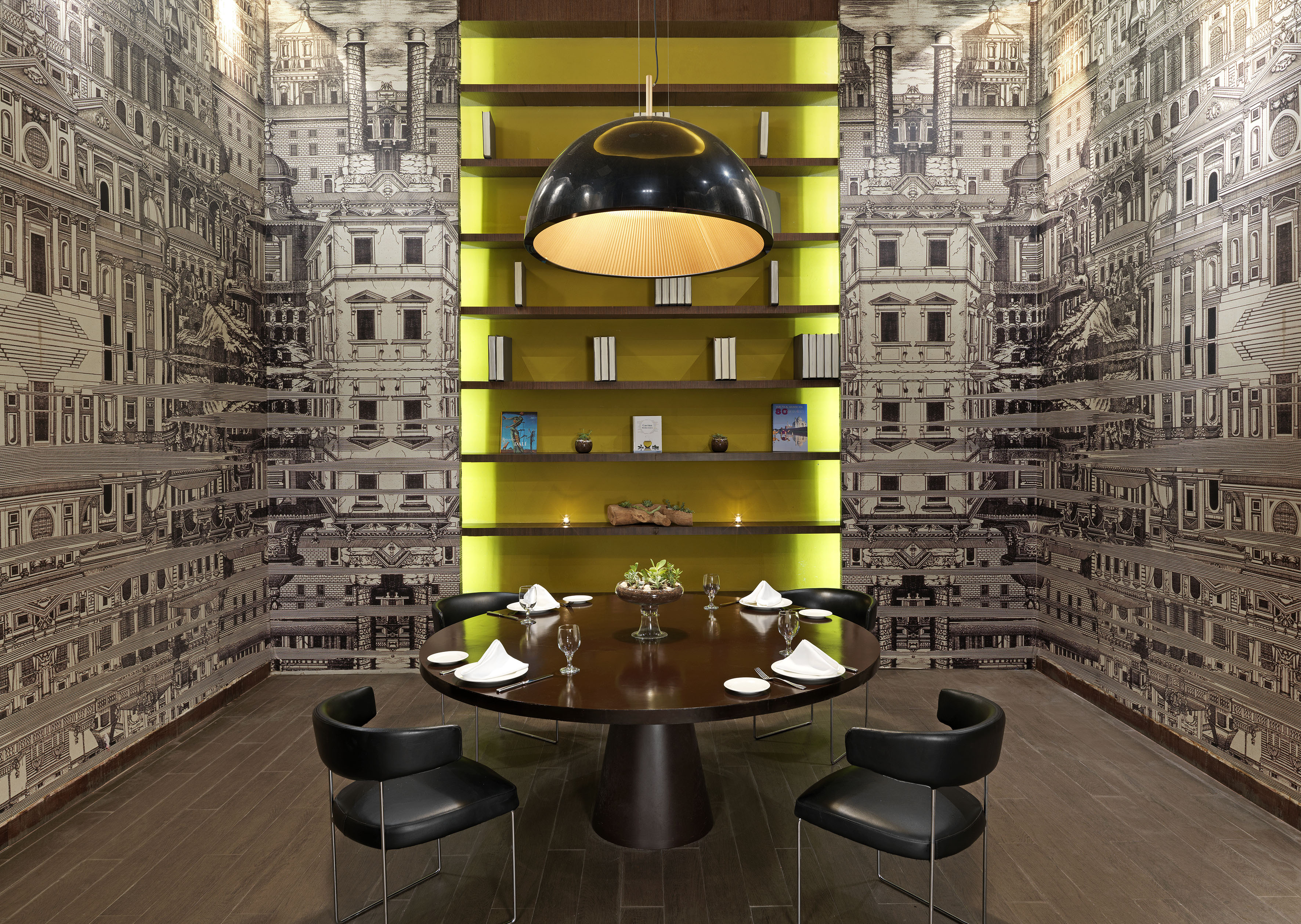 Modern dining room with architectural wallpaper, round table, and yellow shelves.