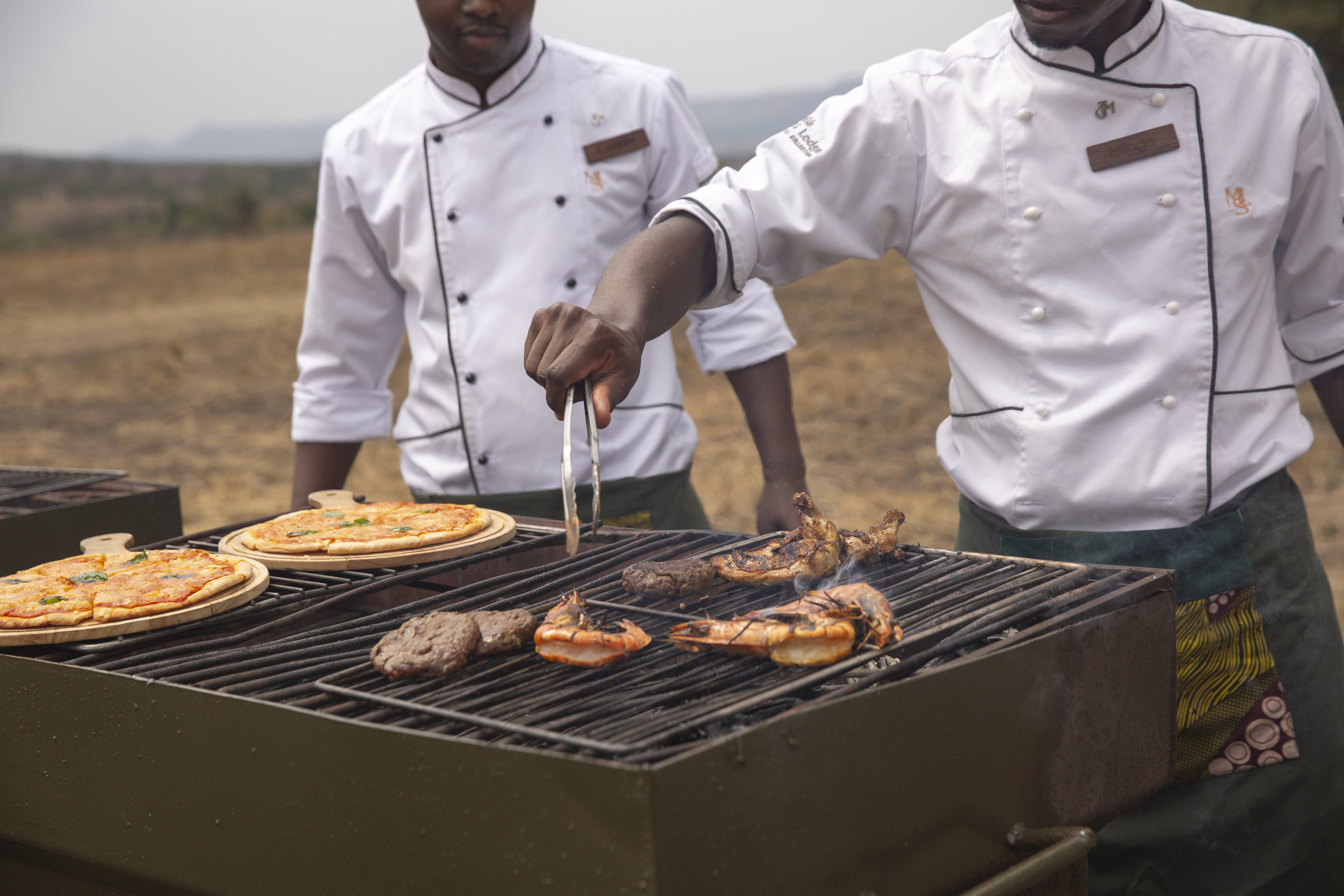 a group of men cooking food on a grill