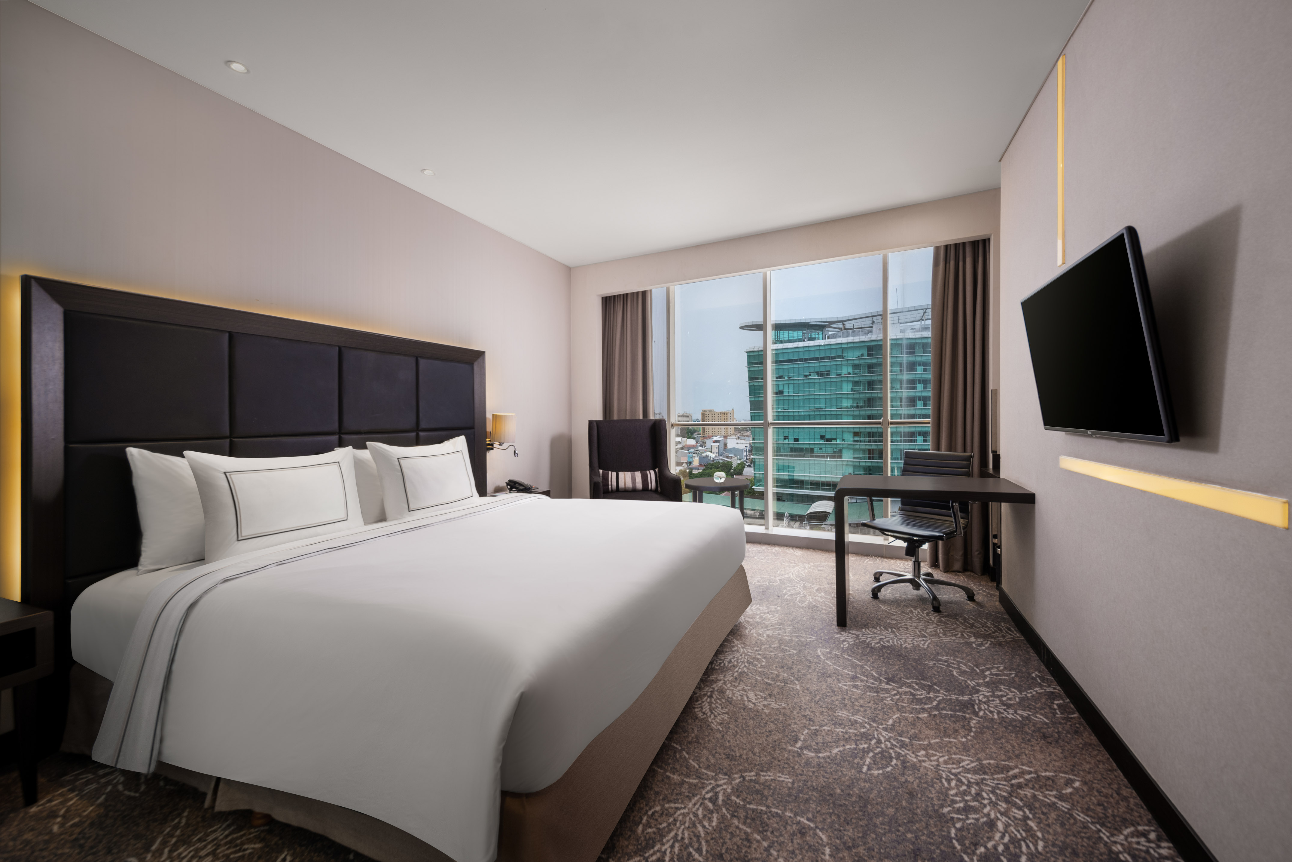 Luxury hotel room with king bed, city skyline view, and workspace.