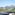 Scenic balcony view of a sunny town, green trees, and distant mountains.