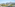 Scenic balcony view of a sunny town, green trees, and distant mountains.