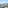 Scenic balcony view of a sunny town, green trees, and distant mountains.