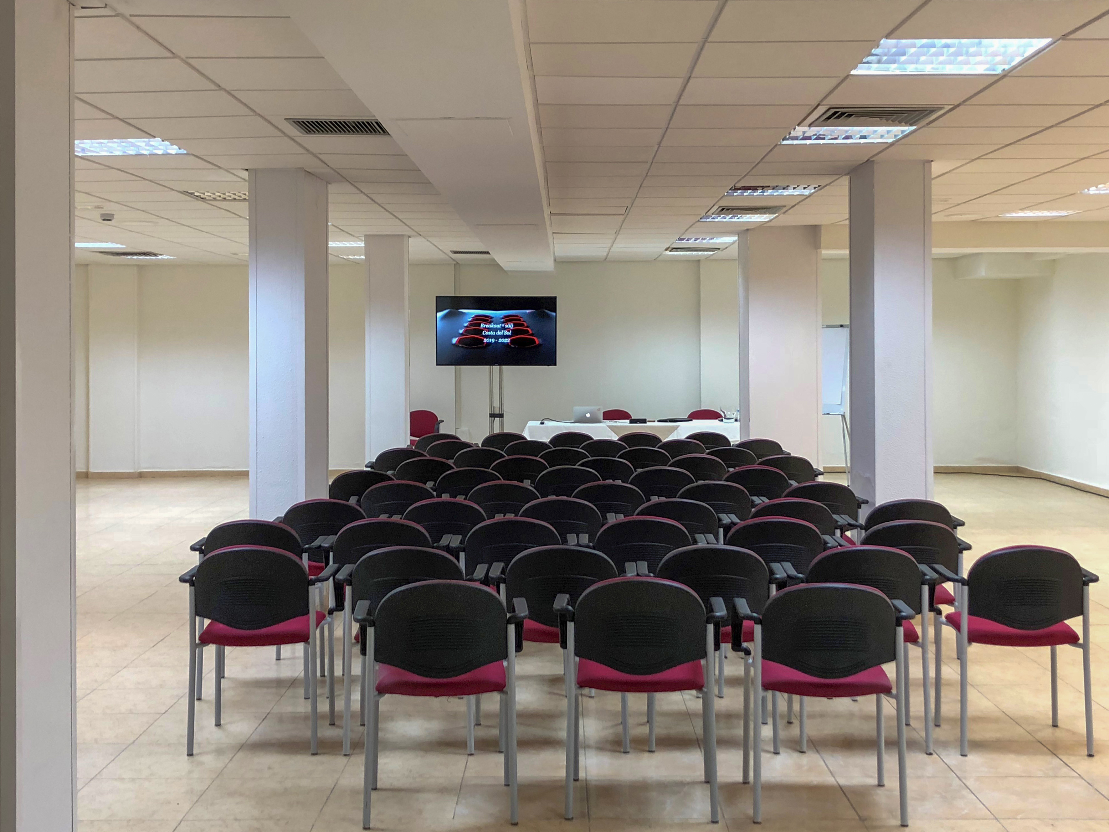 a room with rows of chairs and a television