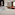 Hotel room with white bed, bubblegum painting, and orange tufted armchairs.