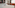 Hotel room with white bed, bubblegum painting, and orange tufted armchairs.