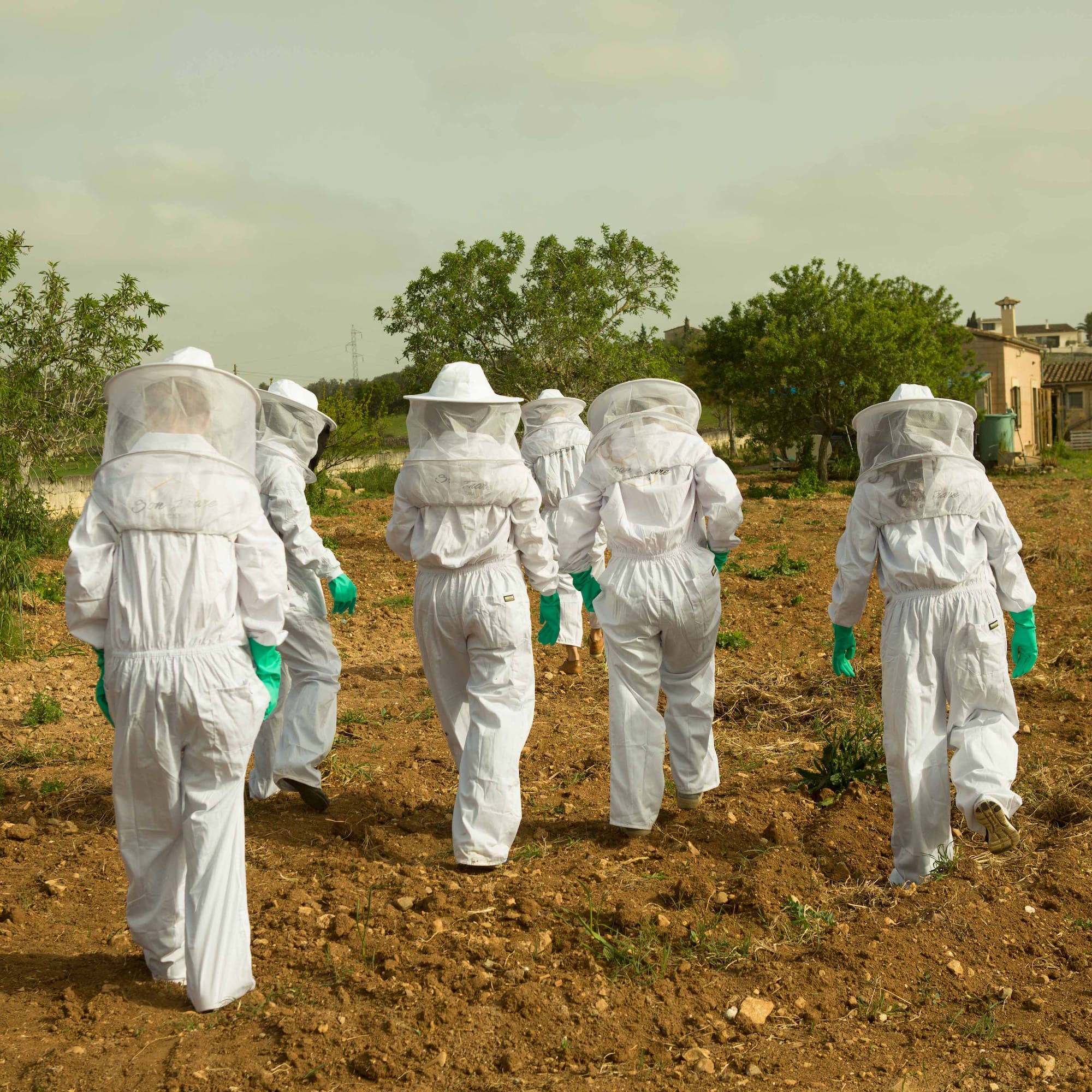 a group of people wearing white protective gear walking in a field