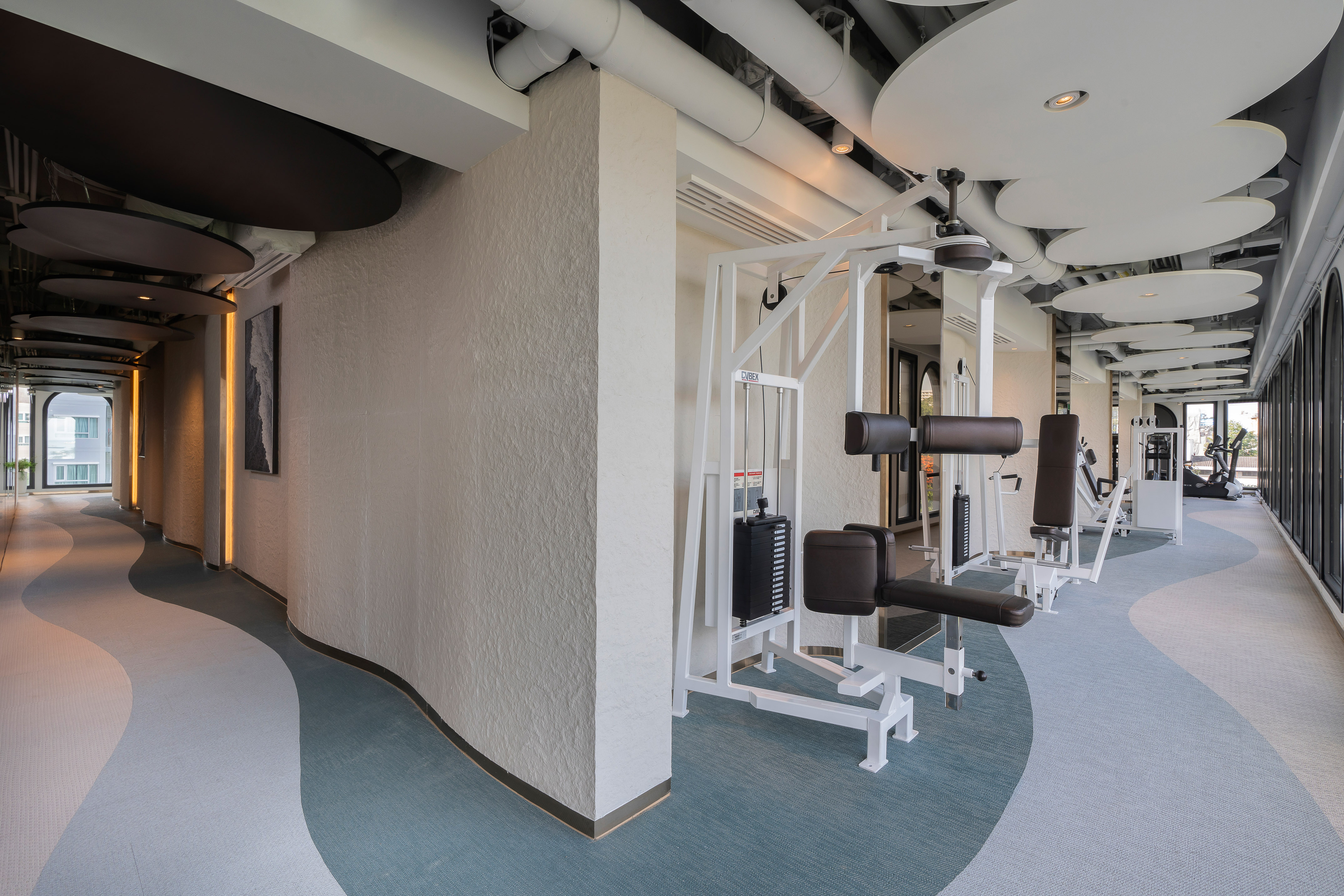 Modern gym with strength machines, cardio equipment, and wavy patterned floor. - Trung tâm thể dục - Meliá Pattaya Hotel, Pattaya