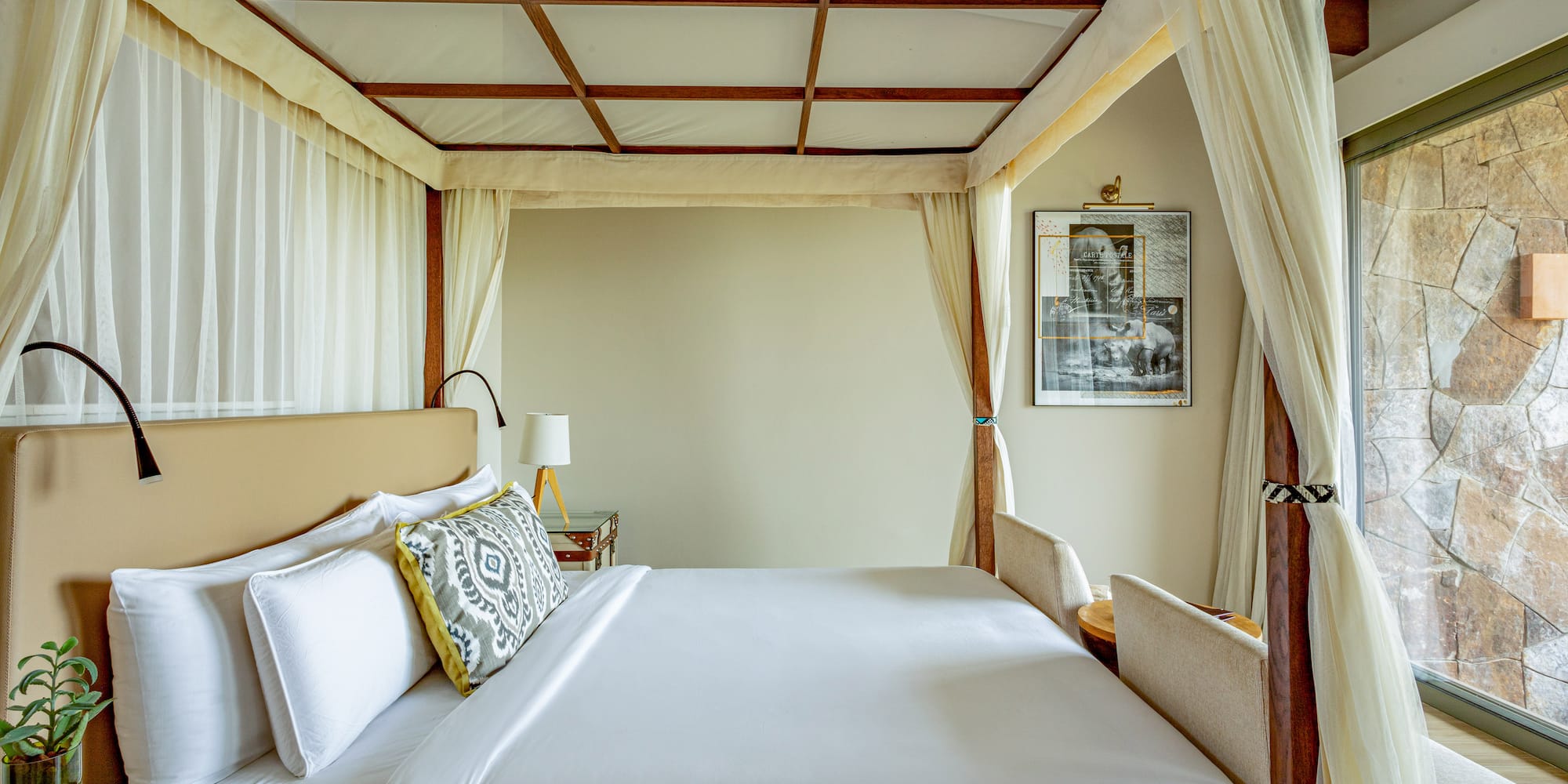 Elegant four-poster canopy bed with white linens and neutral bedroom decor.