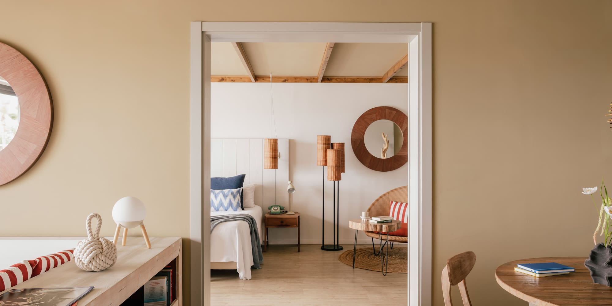 Coastal bedroom through doorway with wooden beams and natural decor.