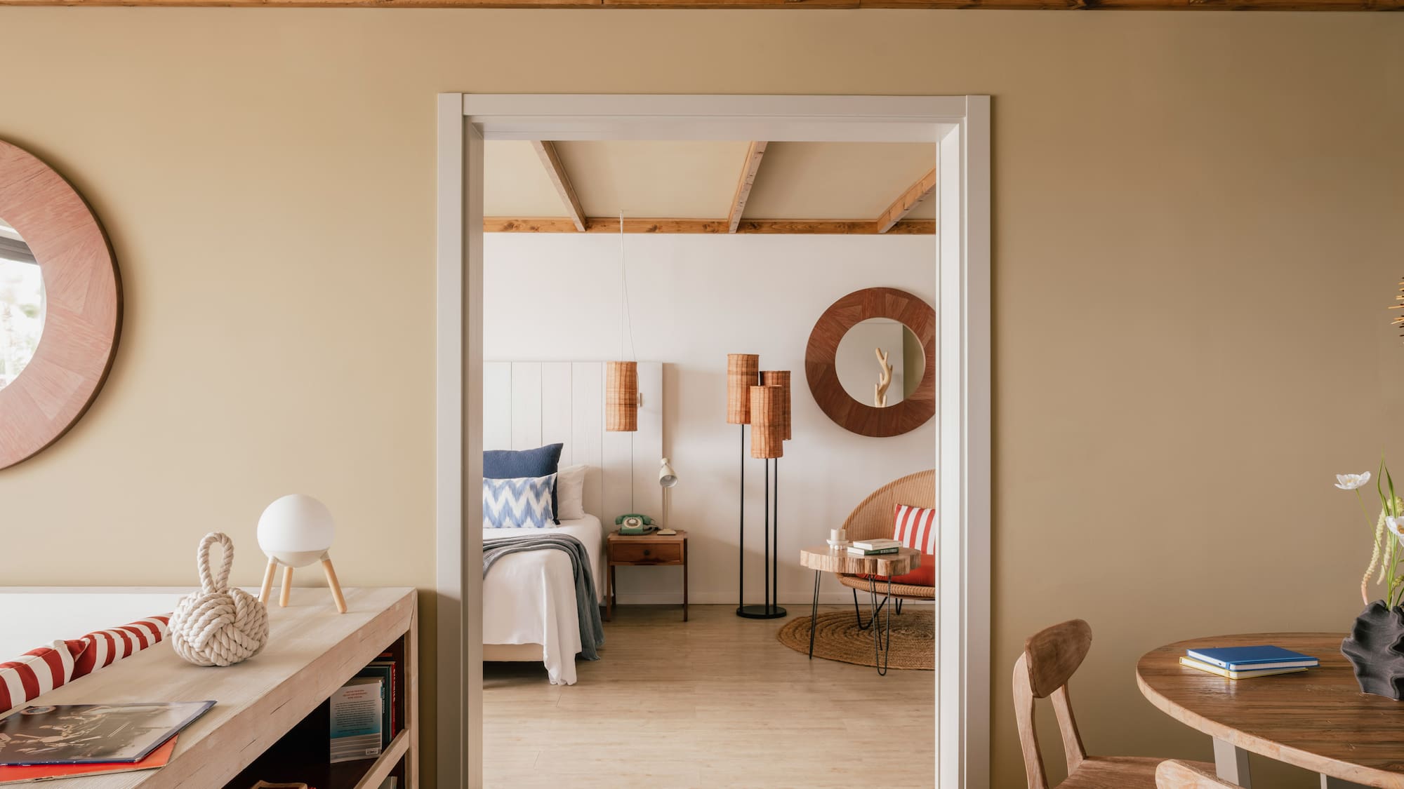 Coastal bedroom through doorway with wooden beams and natural decor.
