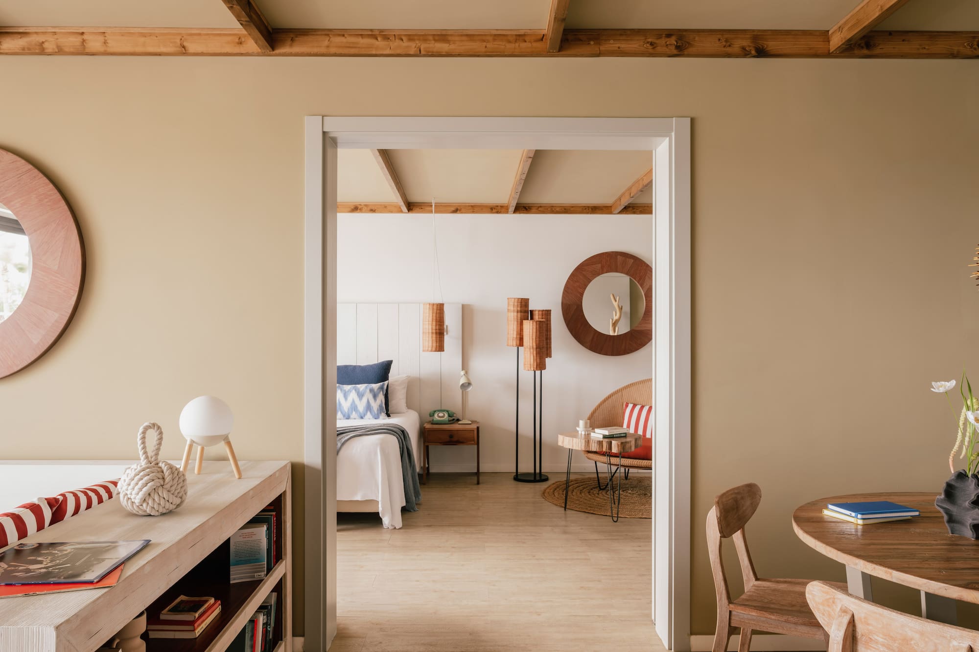 Coastal bedroom through doorway with wooden beams and natural decor.