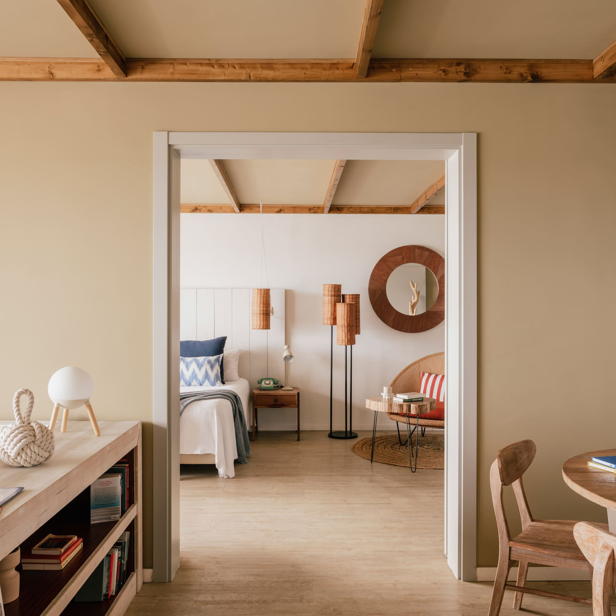 Coastal bedroom through doorway with wooden beams and natural decor.