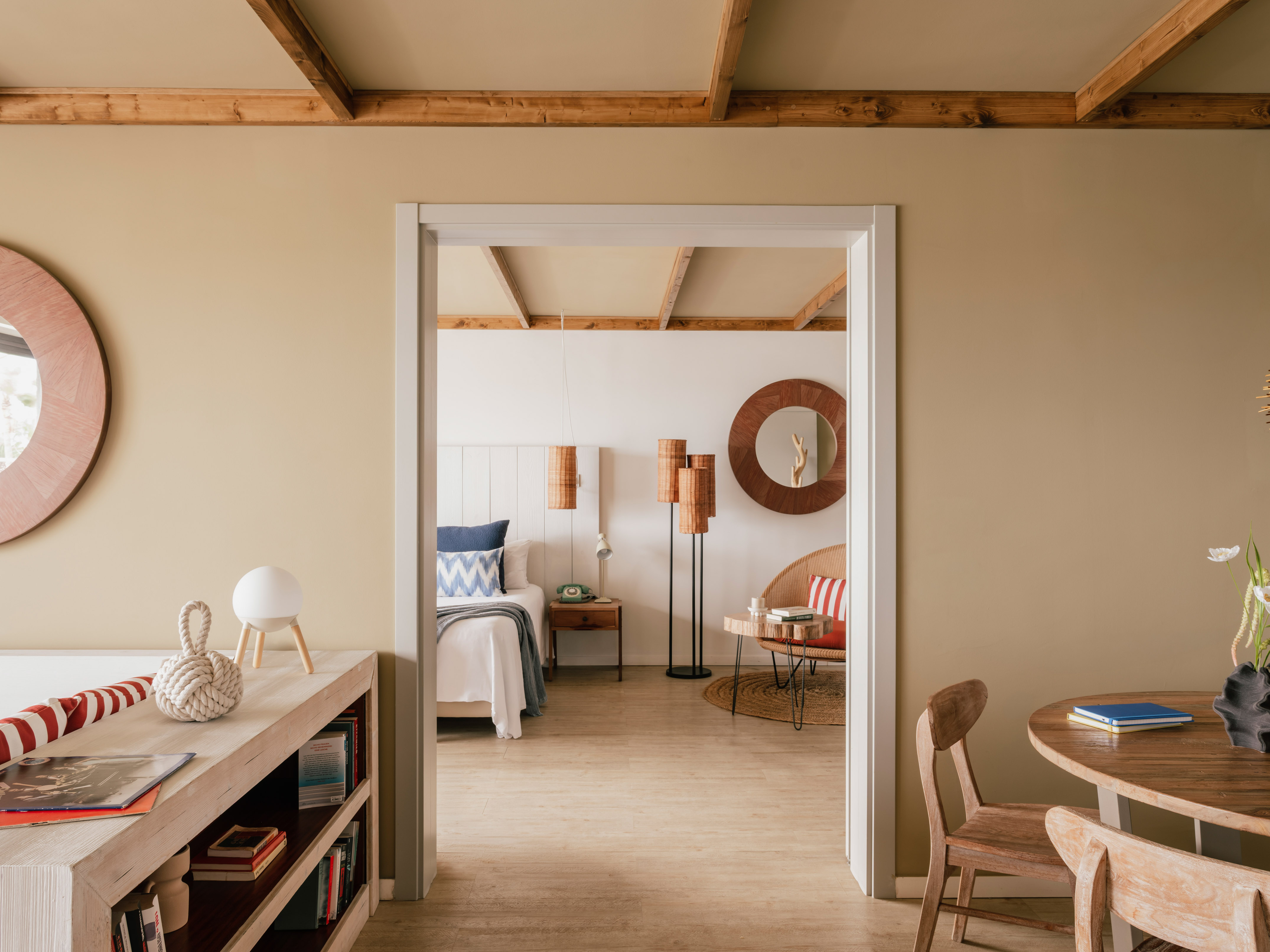 Coastal bedroom through doorway with wooden beams and natural decor.