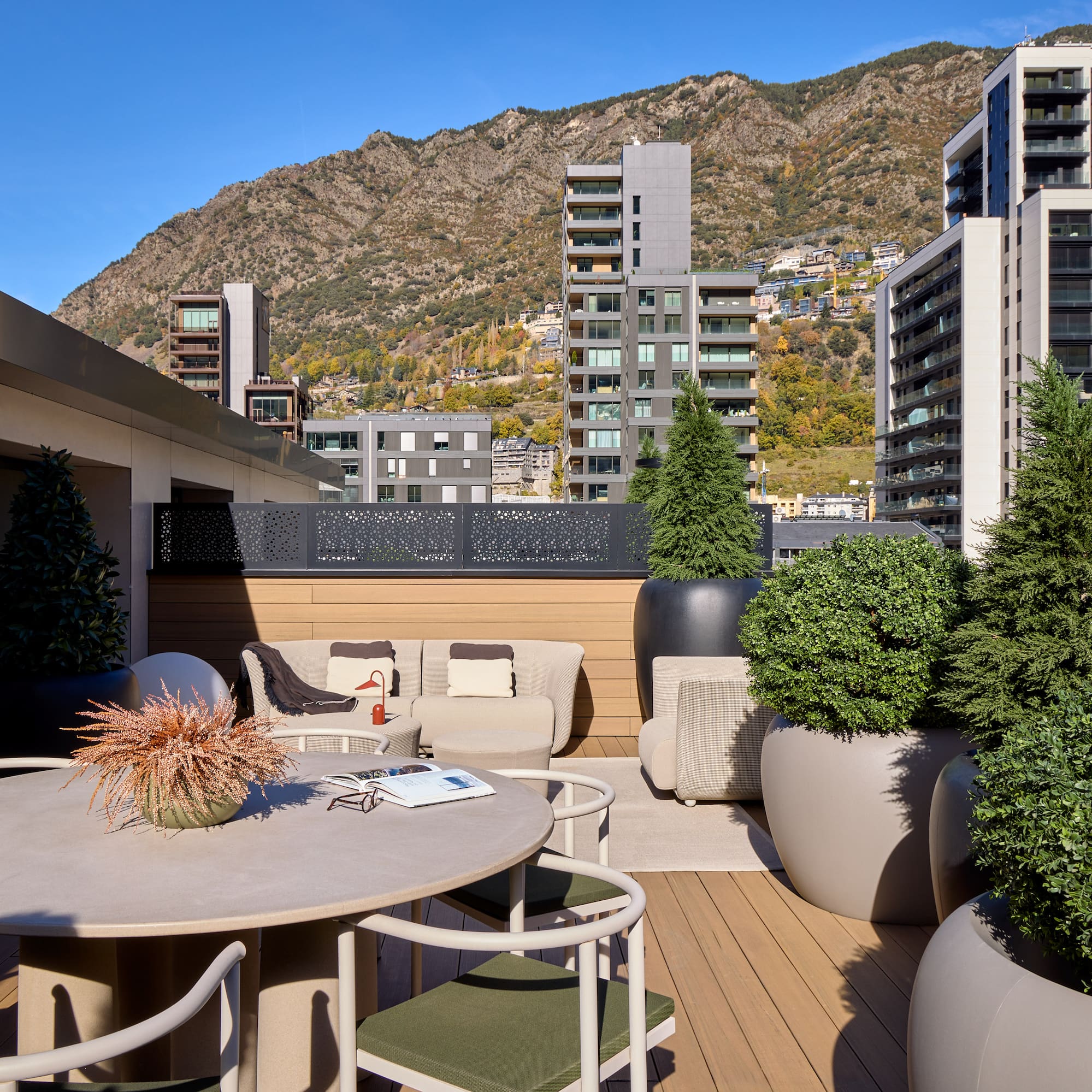 a patio with a table and chairs and trees in pots