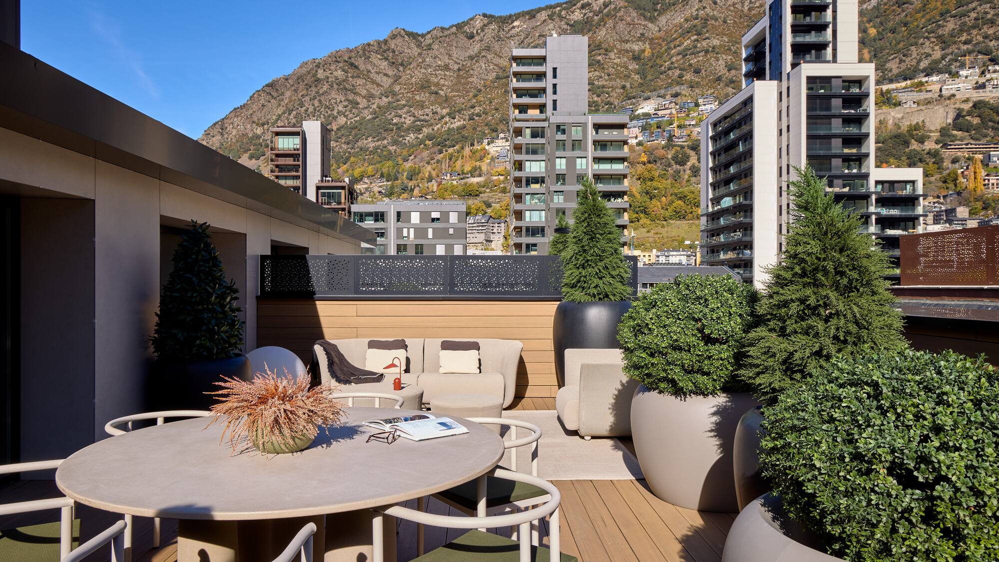 a patio with a table and chairs and trees in pots