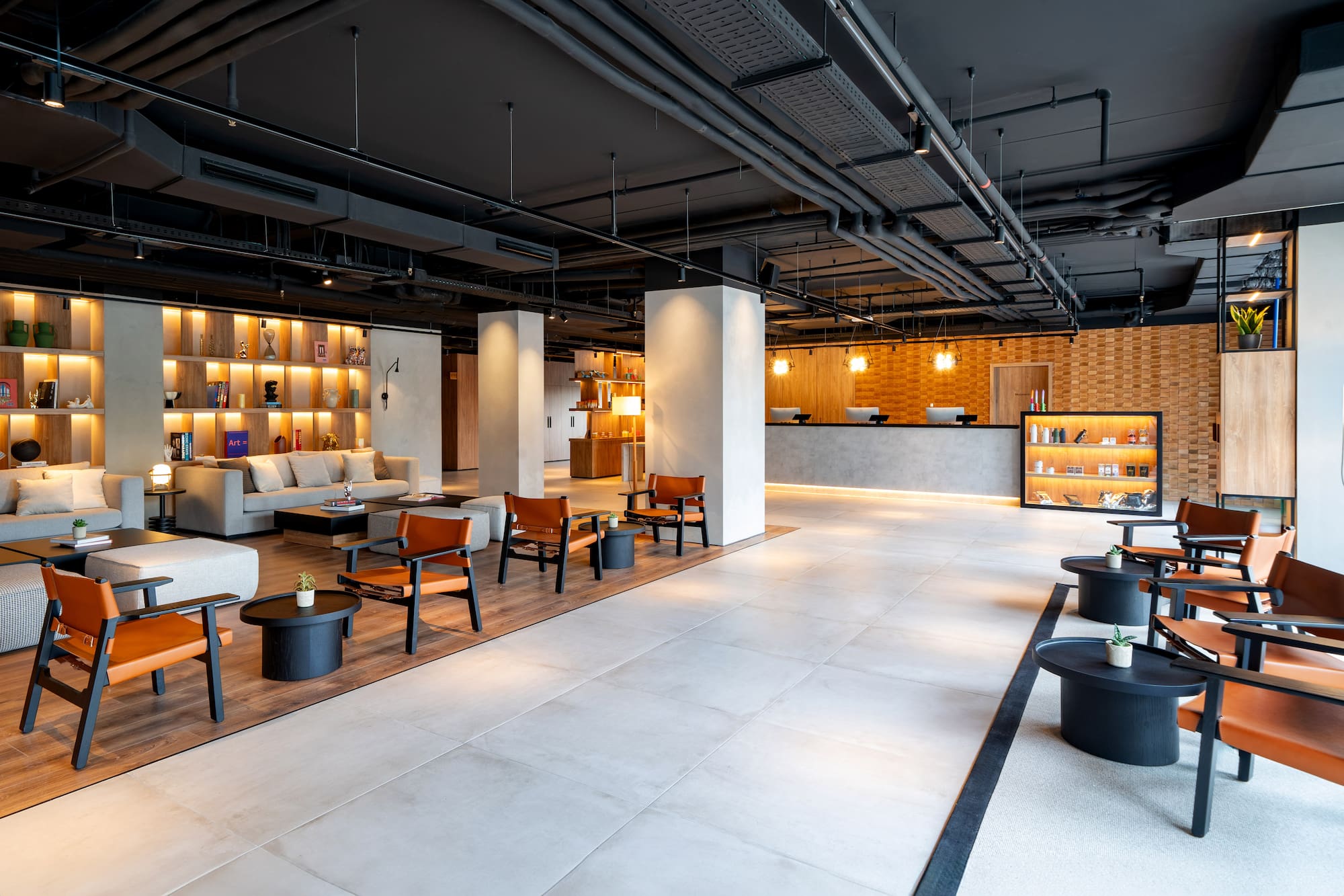 Modern hotel lobby interior with reception, lounge seating, and industrial ceiling.