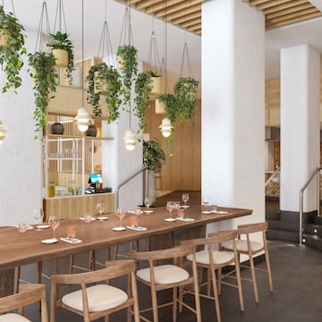 a long table with chairs and a table set in a room with plants from the ceiling