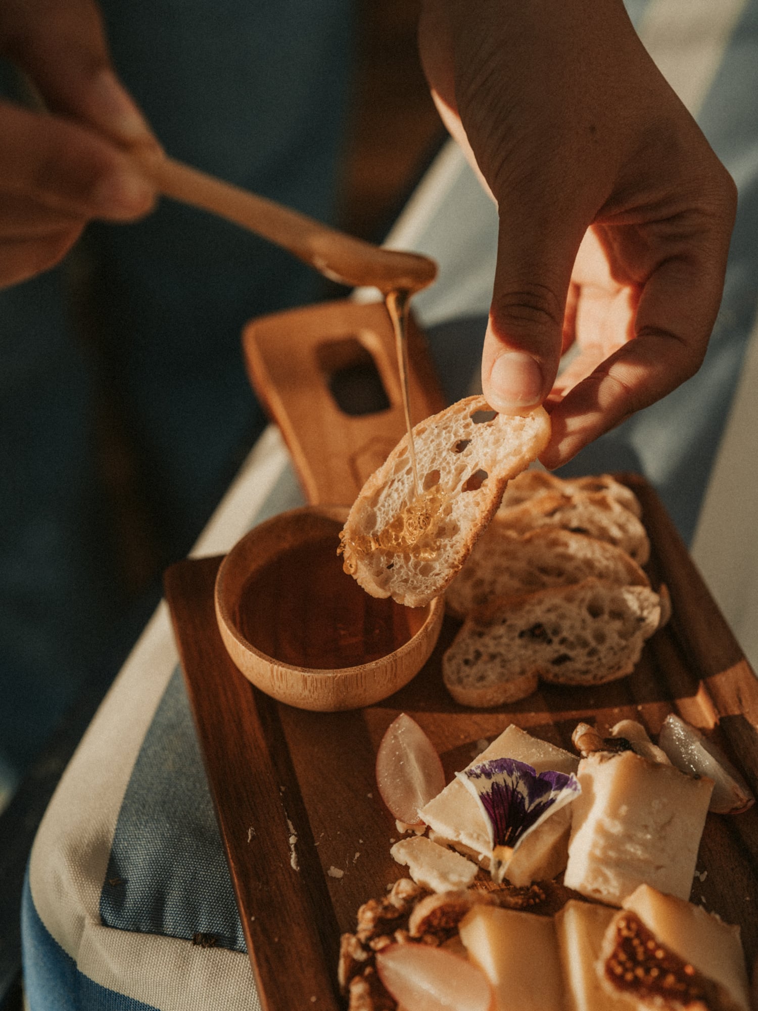 a person pouring honey onto a piece of bread