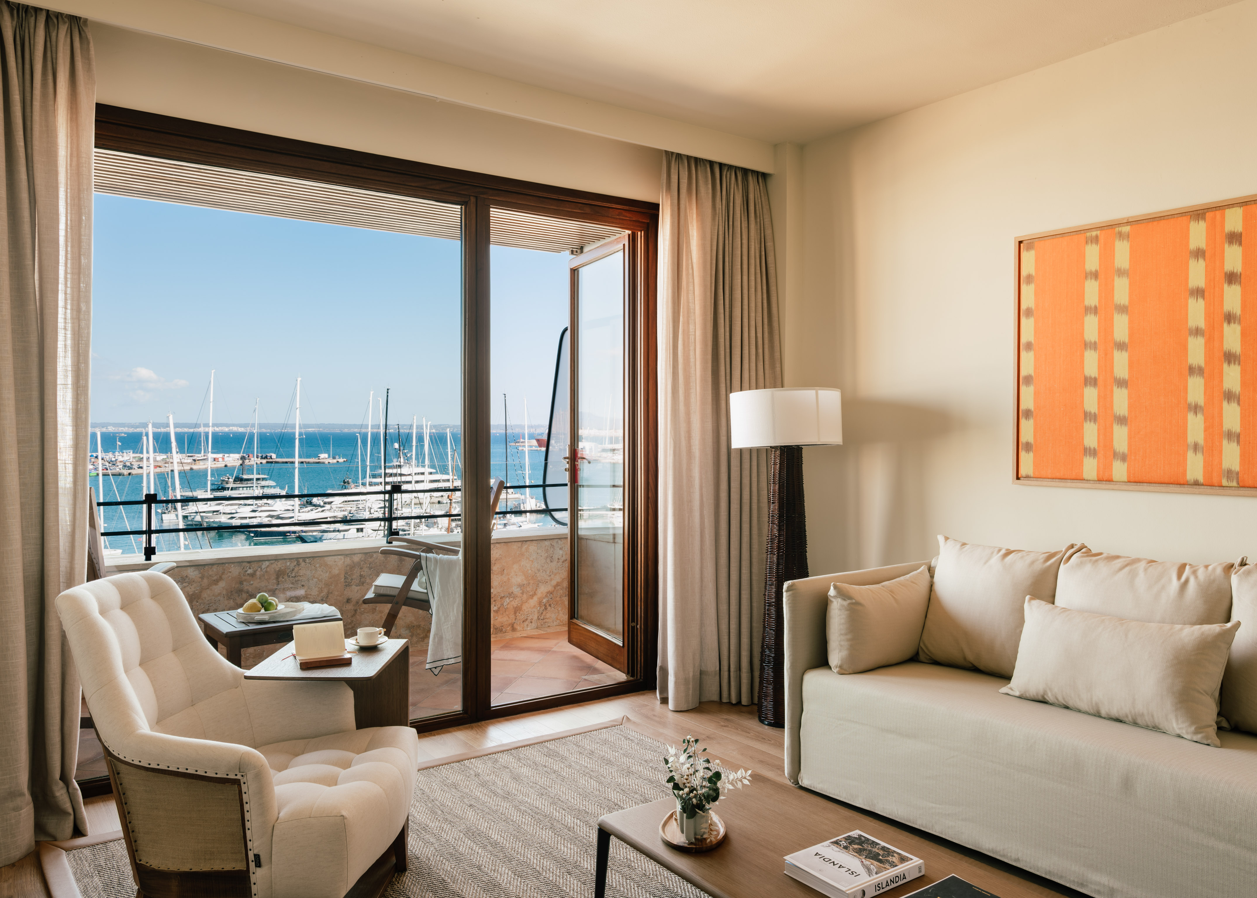 Luxury hotel room with balcony overlooking a marina full of yachts and boats.